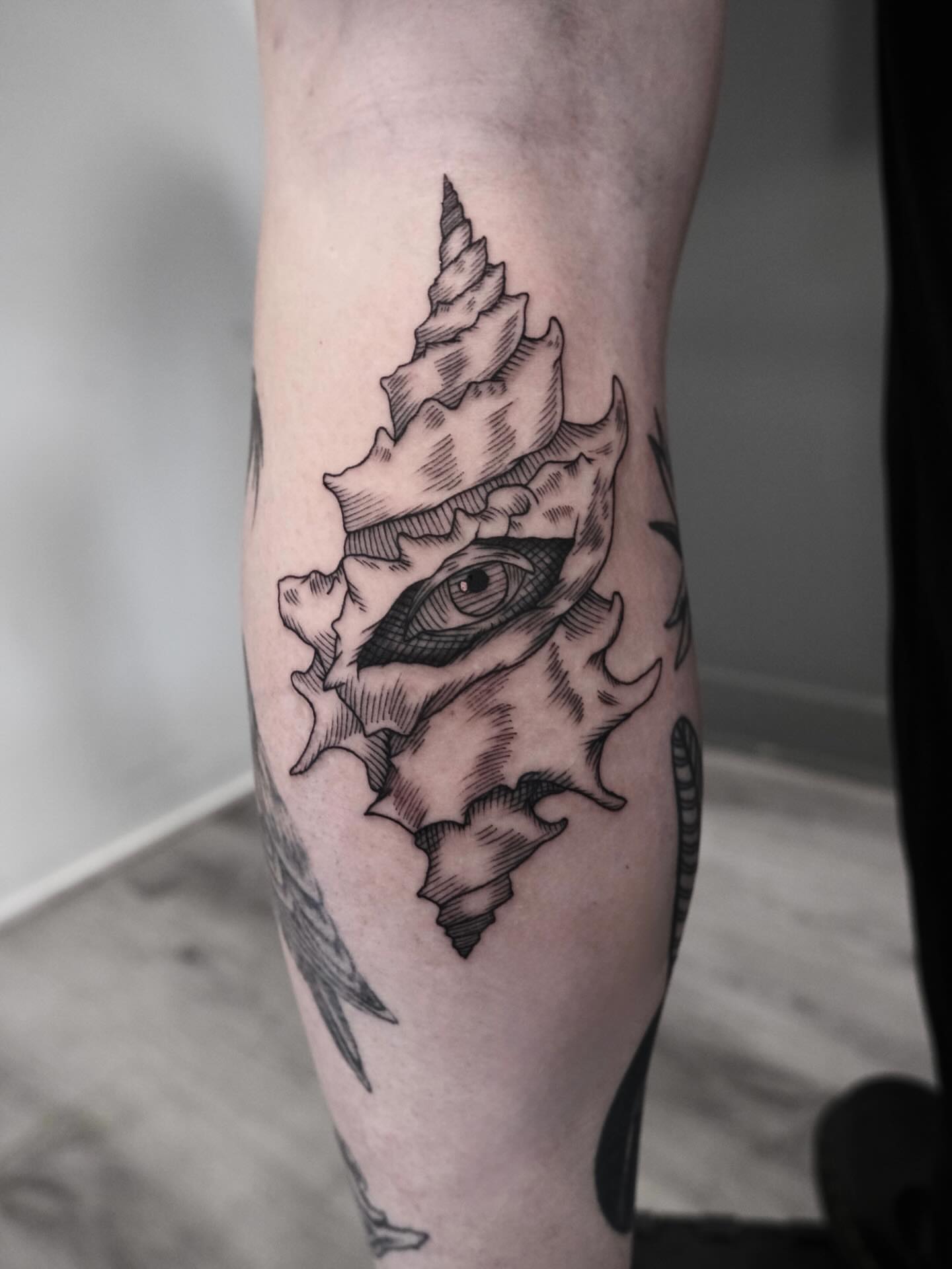Seashell with eye black and grey tattoo on the forearm by Peter(피터)