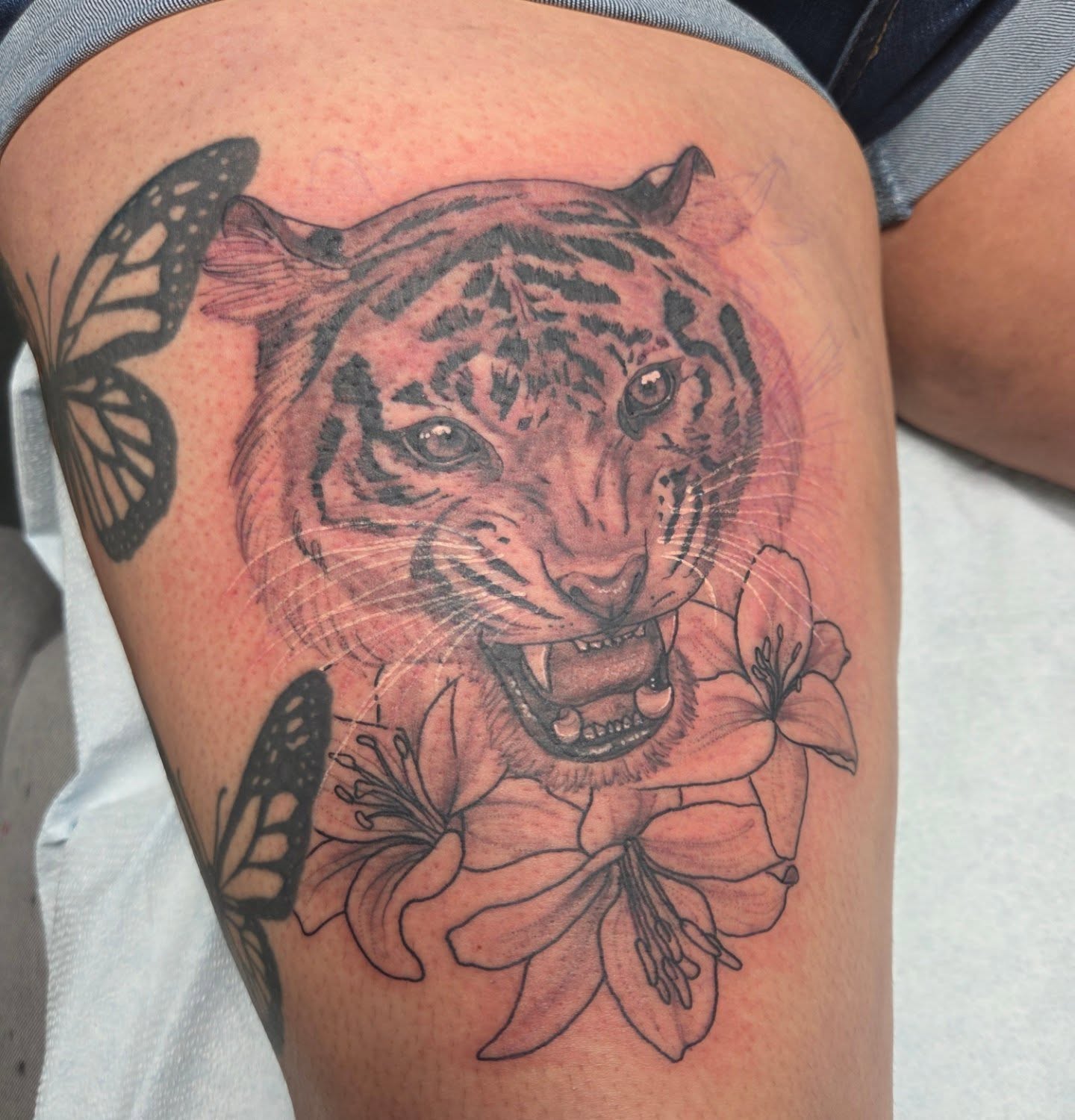 Tiger and flowers realism tattoo on the thigh by Trinity Renee