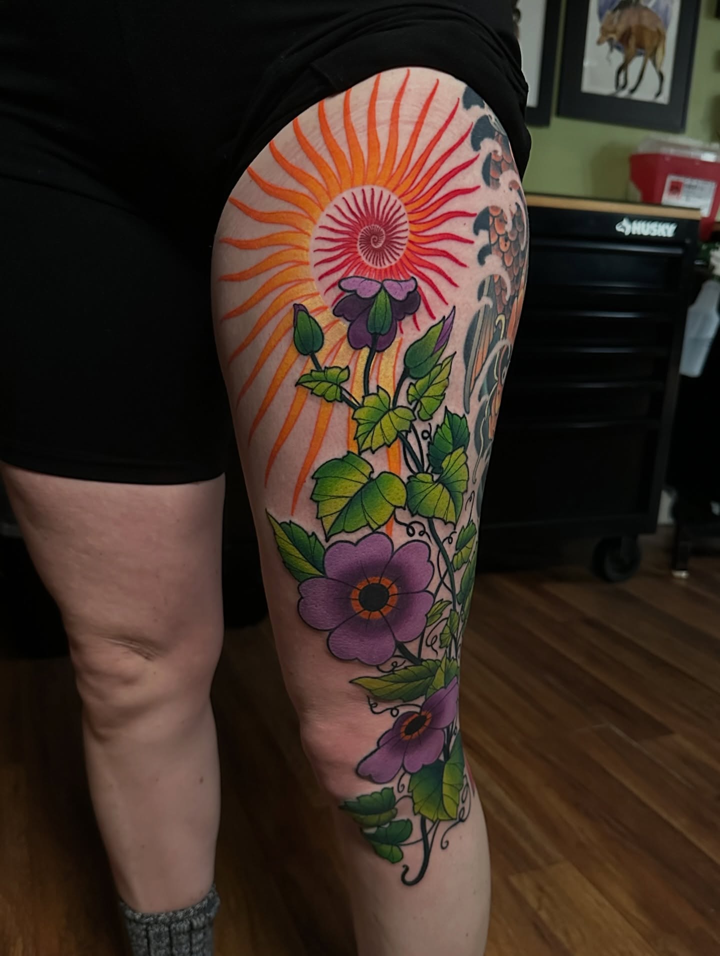 Sunburst and flowers new school tattoo on the thigh by Trevor Burtz