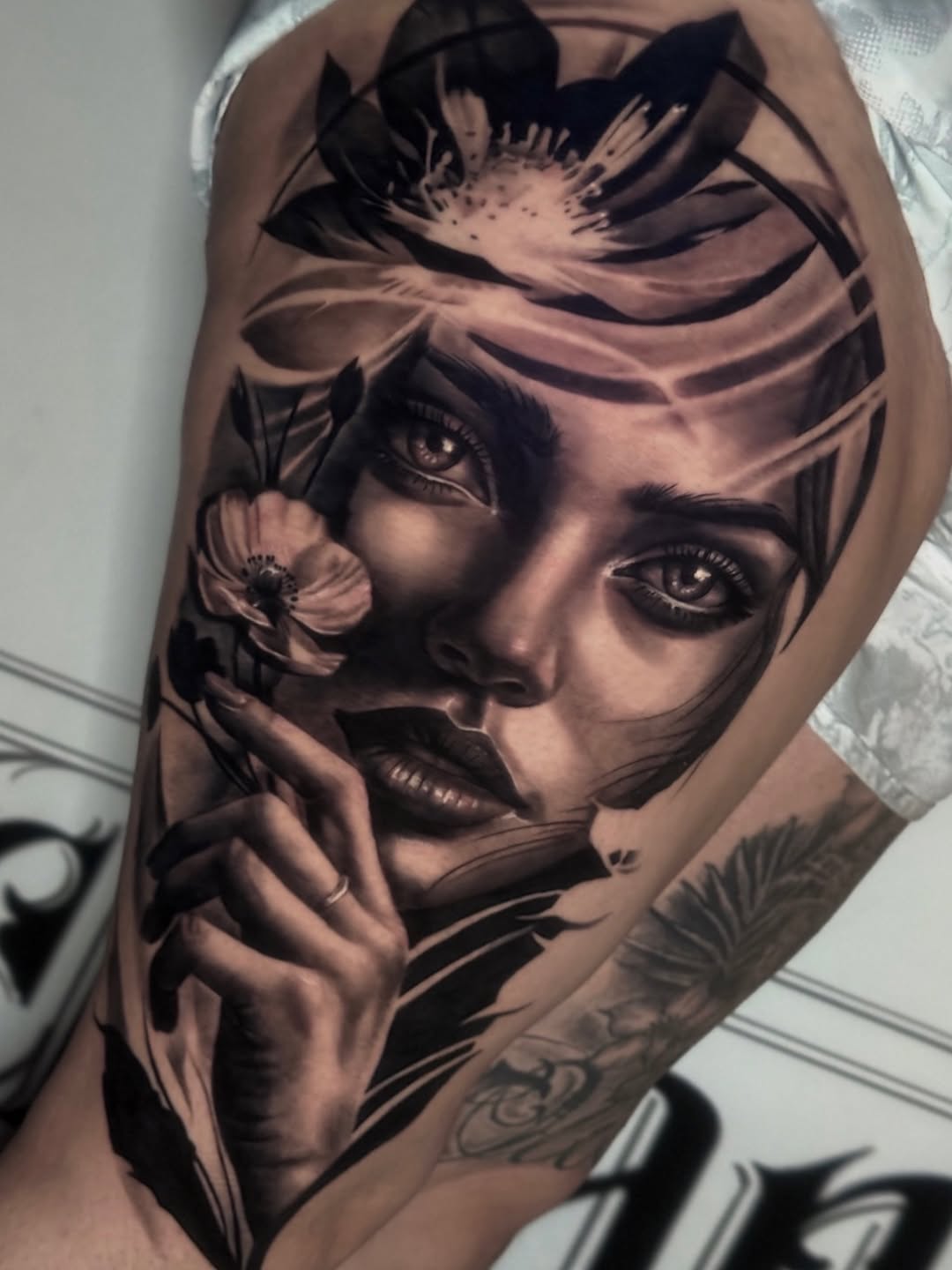 Woman's portrait with flowers realism tattoo on the forearm by Aaron Watson