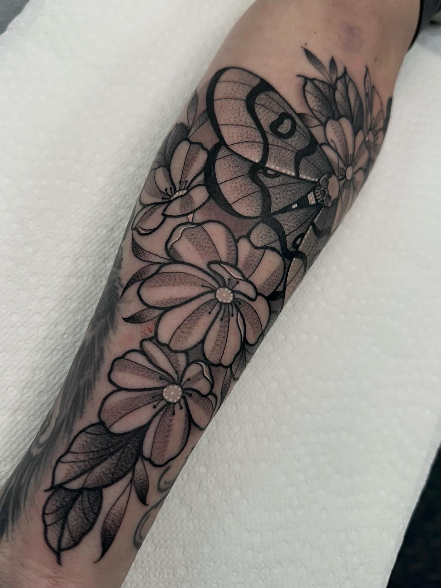 Flowers and butterfly black and grey tattoo on the forearm by Katie Kelley