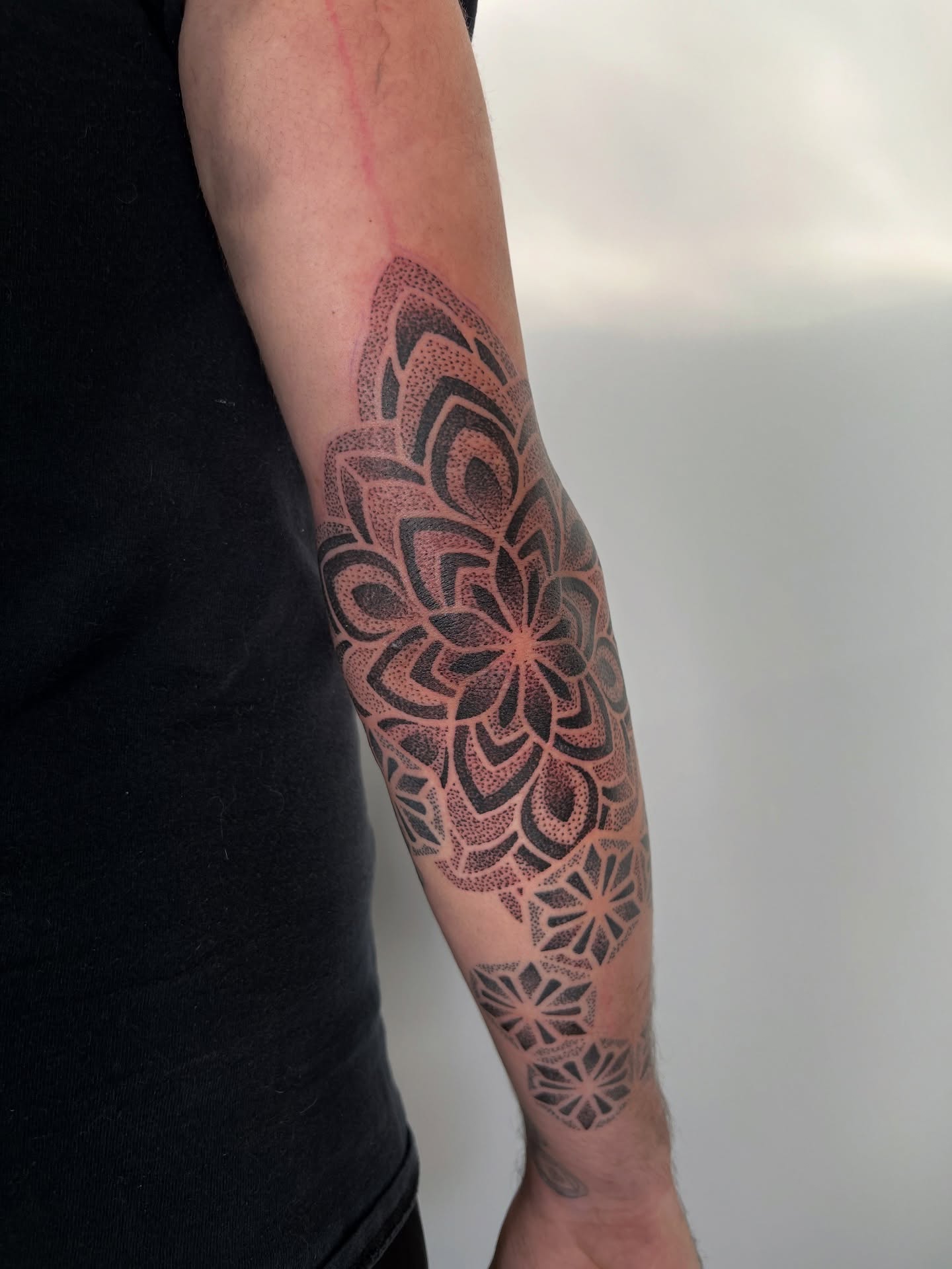 Geometric mandala dotwork tattoo on the forearm by Riley