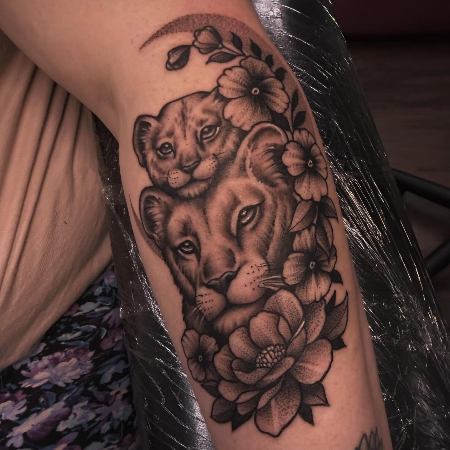 Lioness and cub with flowers realism tattoo on the forearm by Sarah Foltz