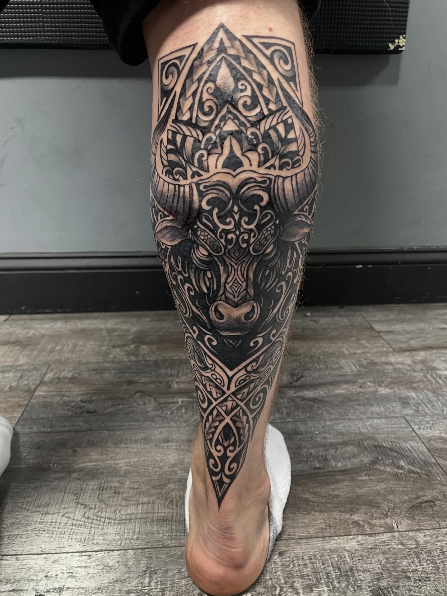 Bull head geometric tattoo on the calf by Shaunboweink