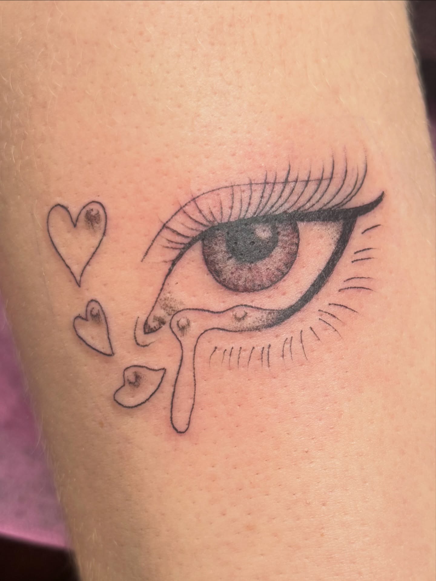 Tearful eye with hearts realism tattoo on the forearm by Teagan Rachel, Millcreek, Utah