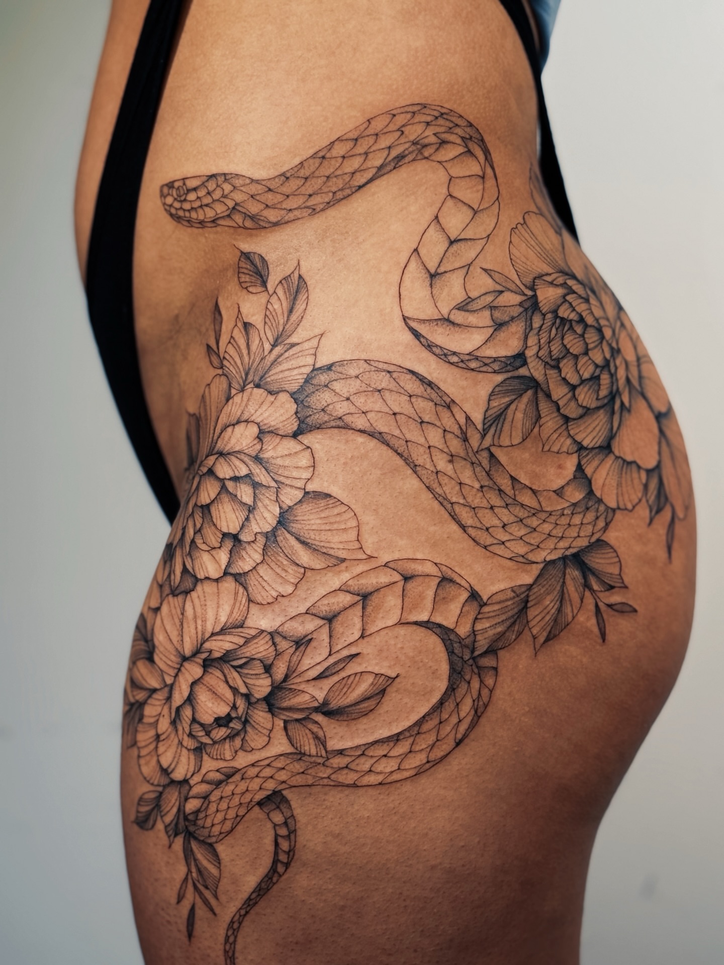Snake and peony realism tattoo on the thigh by Olha Tytarenko