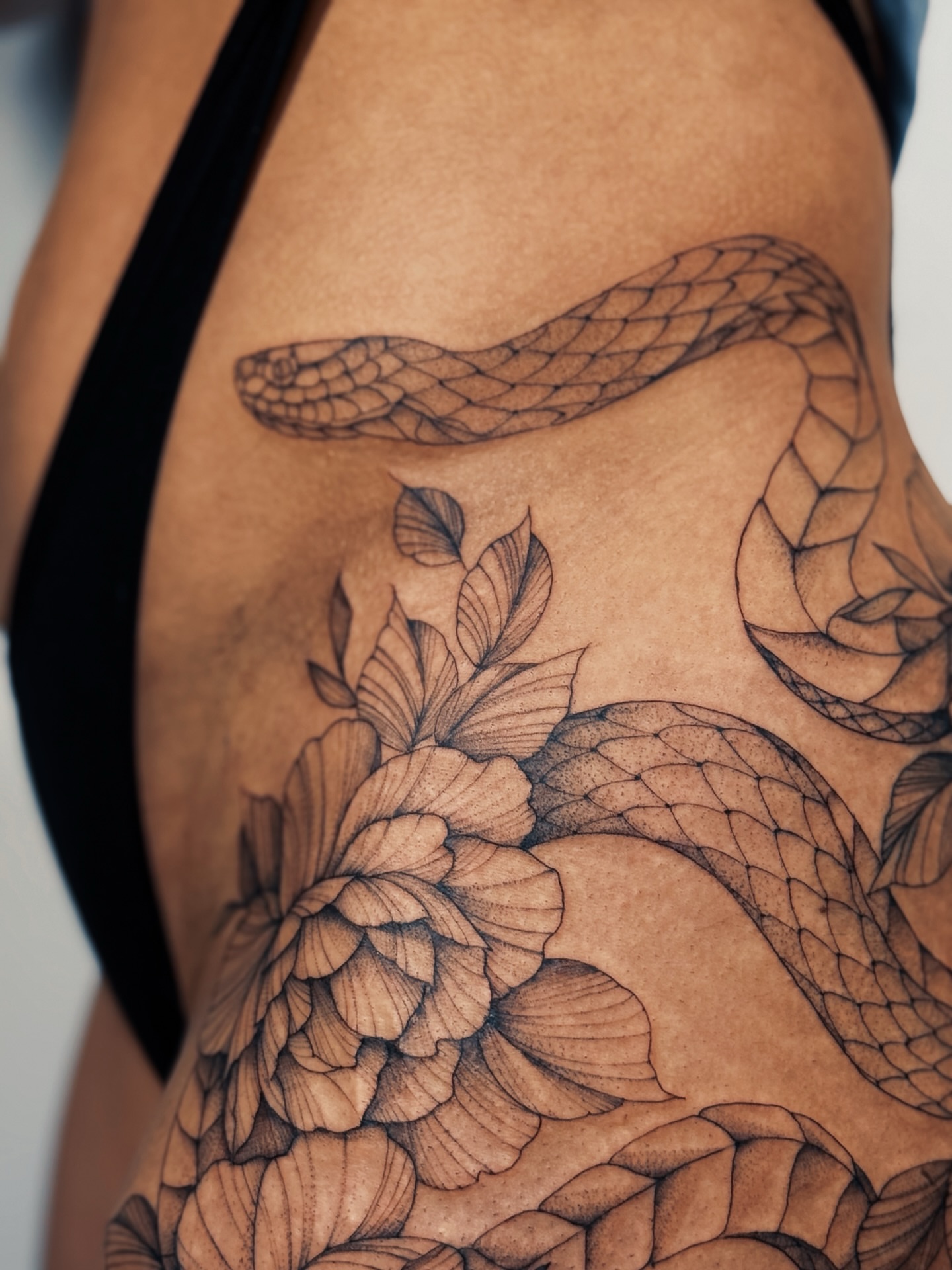 Snake and peony black and grey tattoo on the thigh by Olha Tytarenko