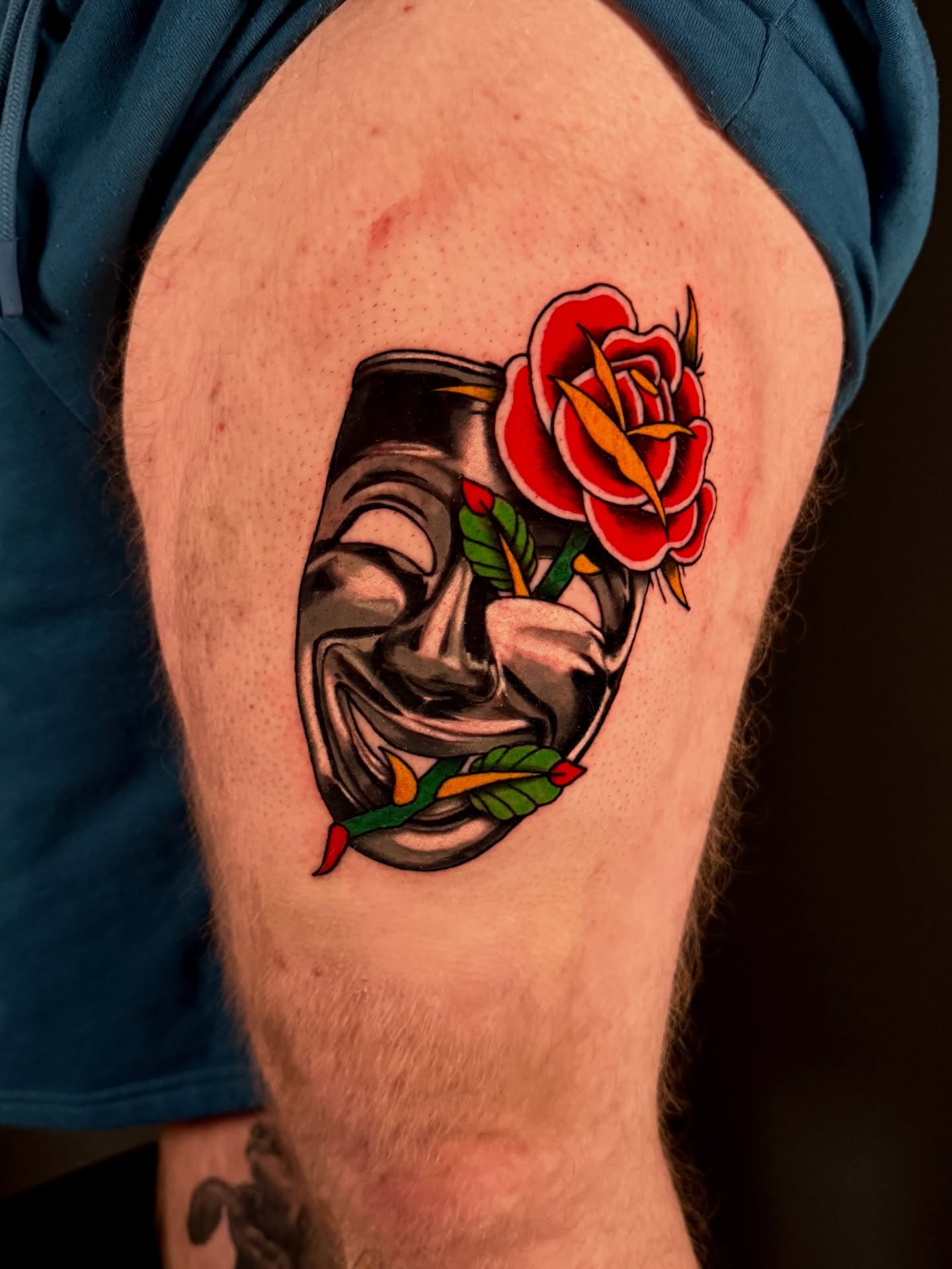 Theater mask and rose American traditional tattoo on the thigh by Dallas Tattoo Artist