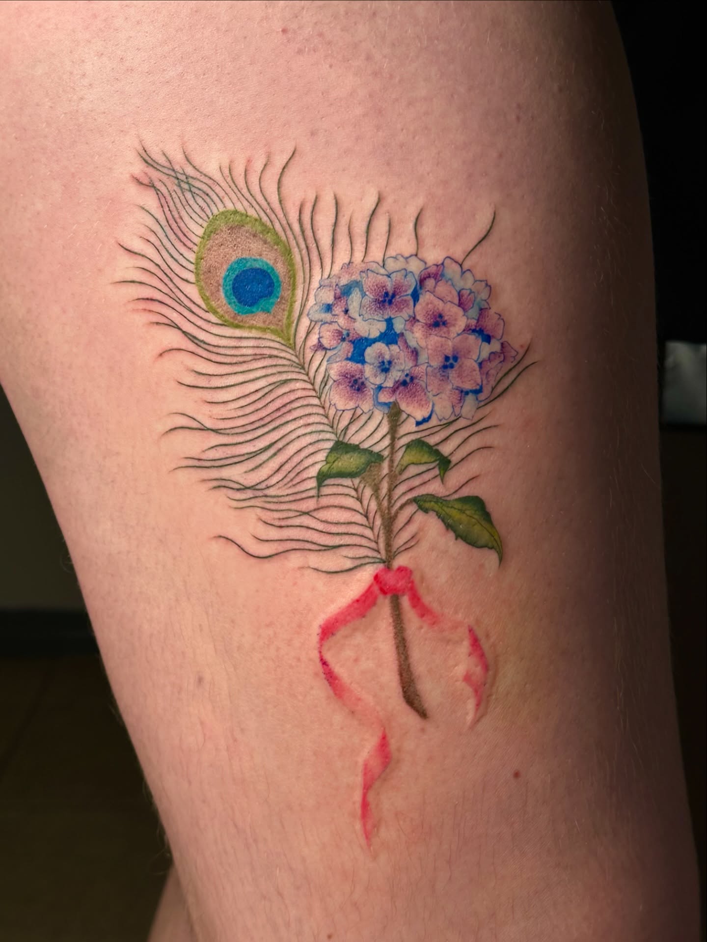 Peacock feather and hydrangea realism tattoo on the thigh by Isla Araoz <3