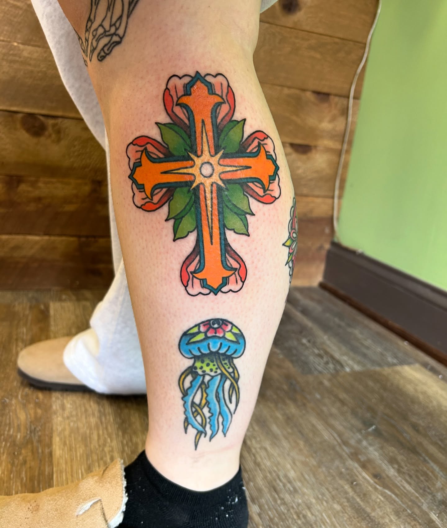 Cross with jellyfish American traditional tattoo on the calf by Courtney