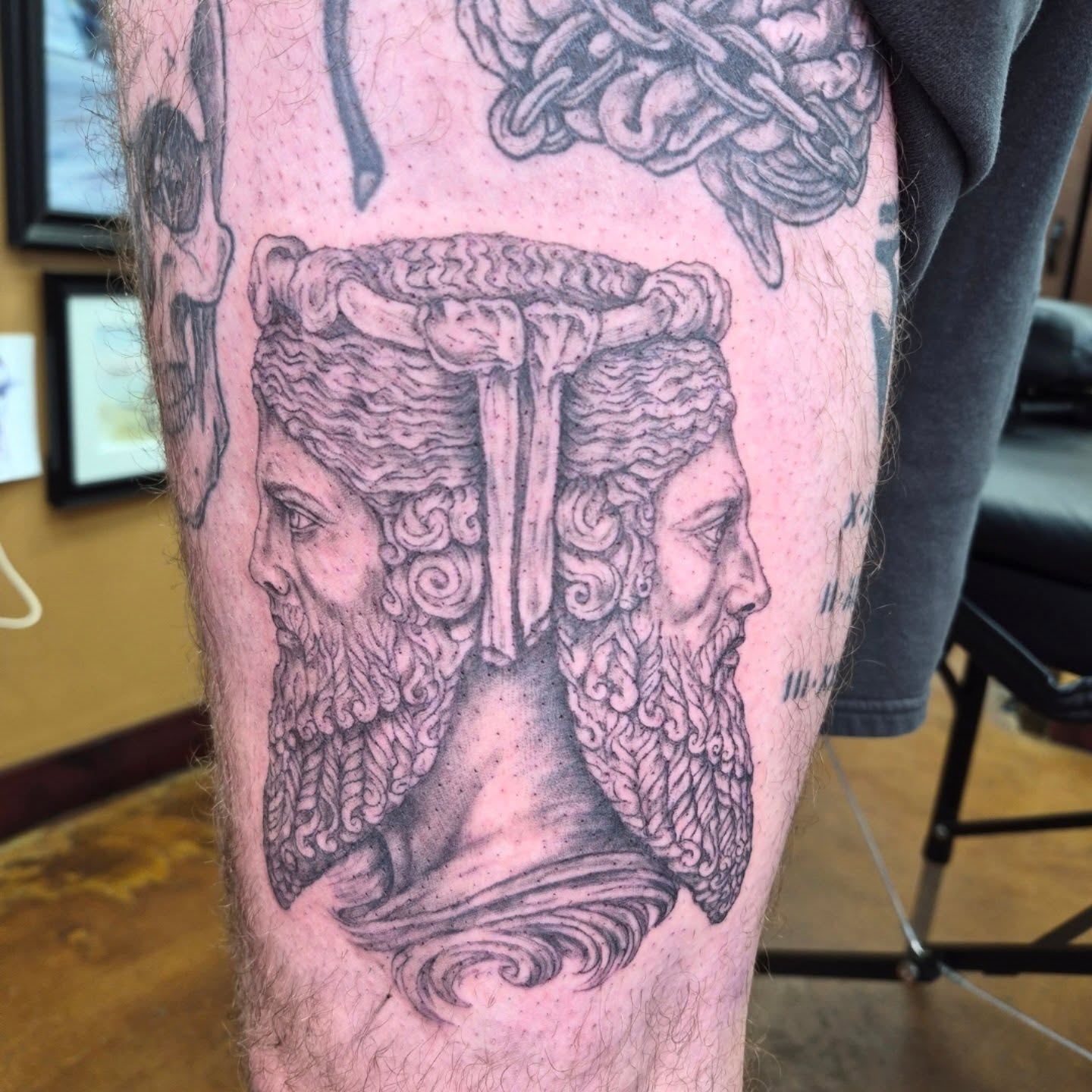 Bearded heads black and grey tattoo on the thigh by Chris Bell