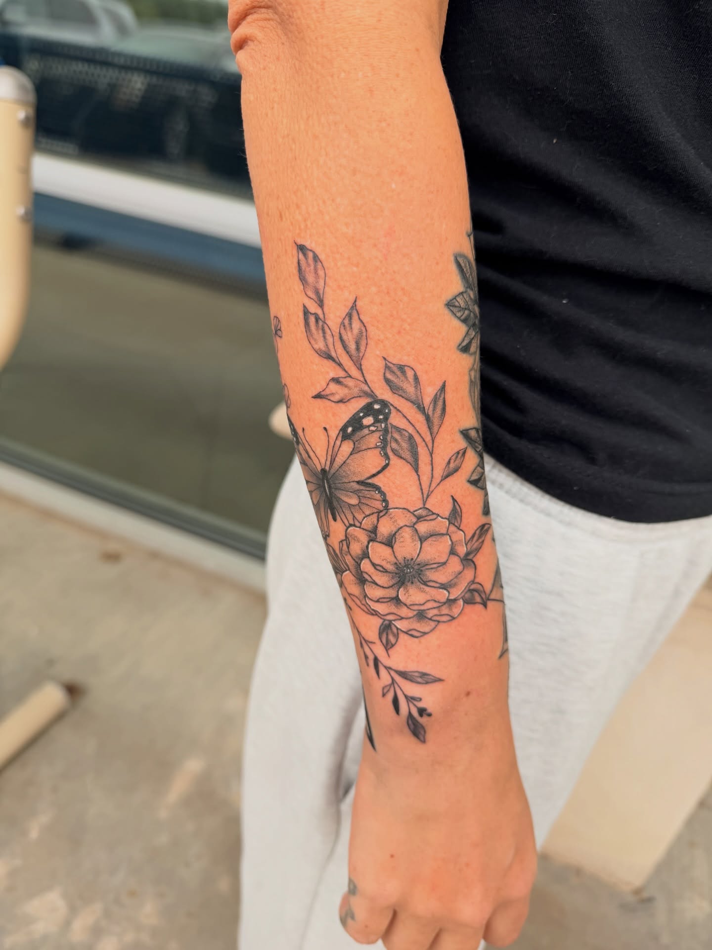 Butterfly and flowers black and grey tattoo on the forearm by Lexi Odam