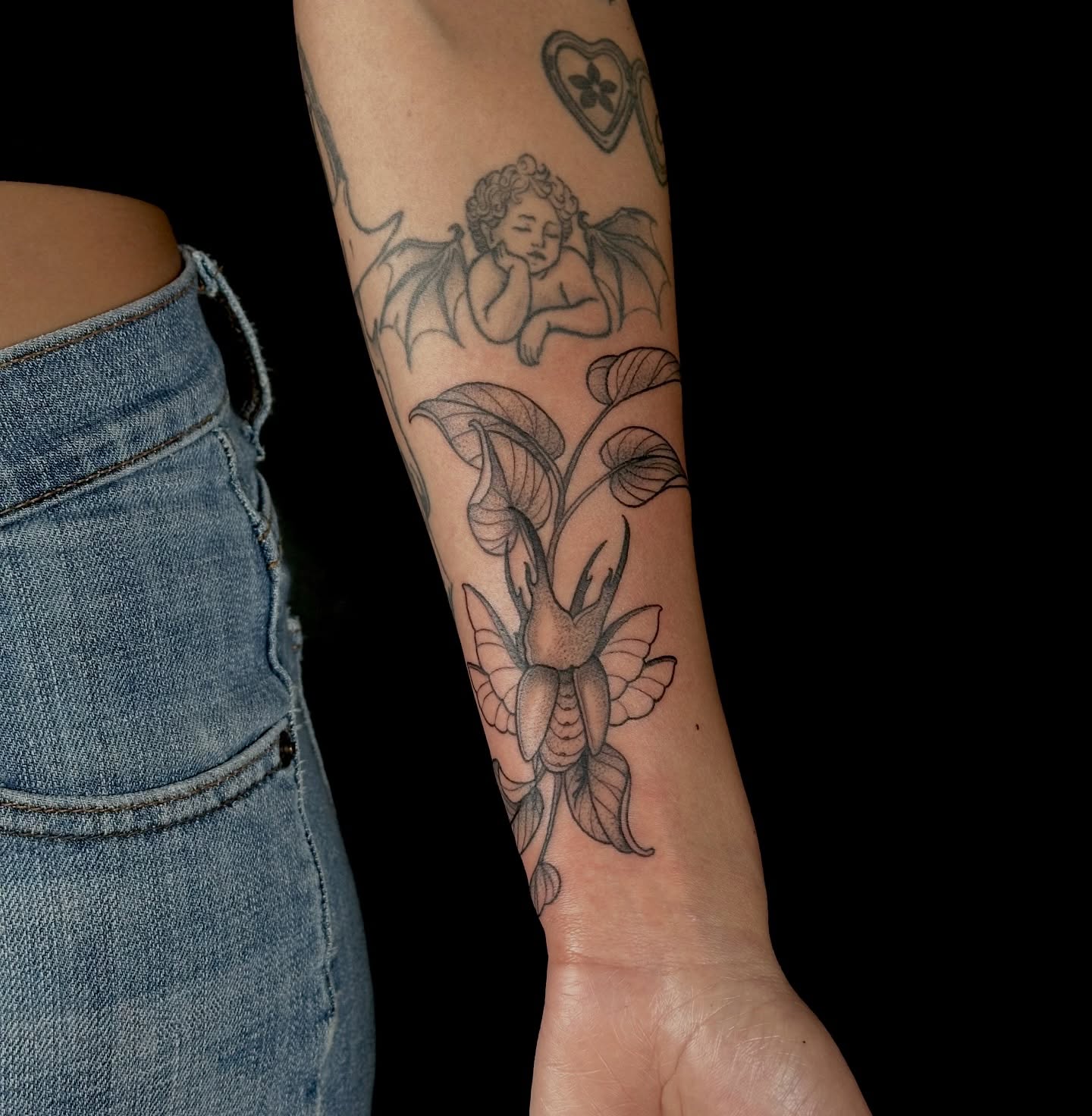 Cherub and calla lily black and grey tattoo on the forearm by Zoe Arrigo
