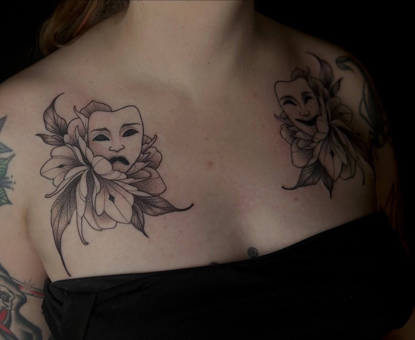 Theater masks and flowers black and grey tattoo on the chest by Zoe Arrigo