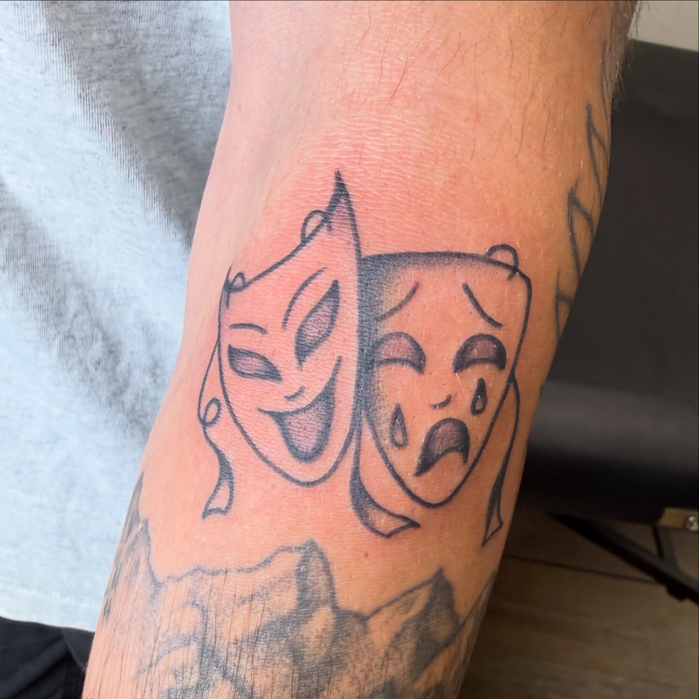 Theater masks black and grey tattoo on the forearm by Kaysen