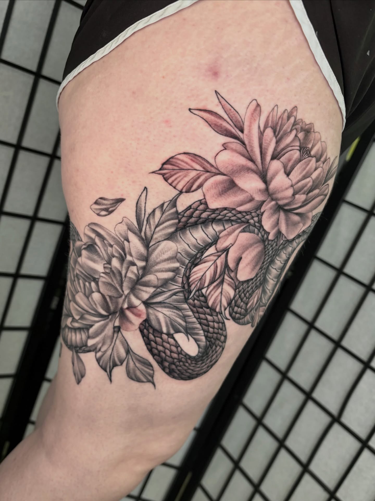Snake and peony realism tattoo on the thigh by hannah vertal