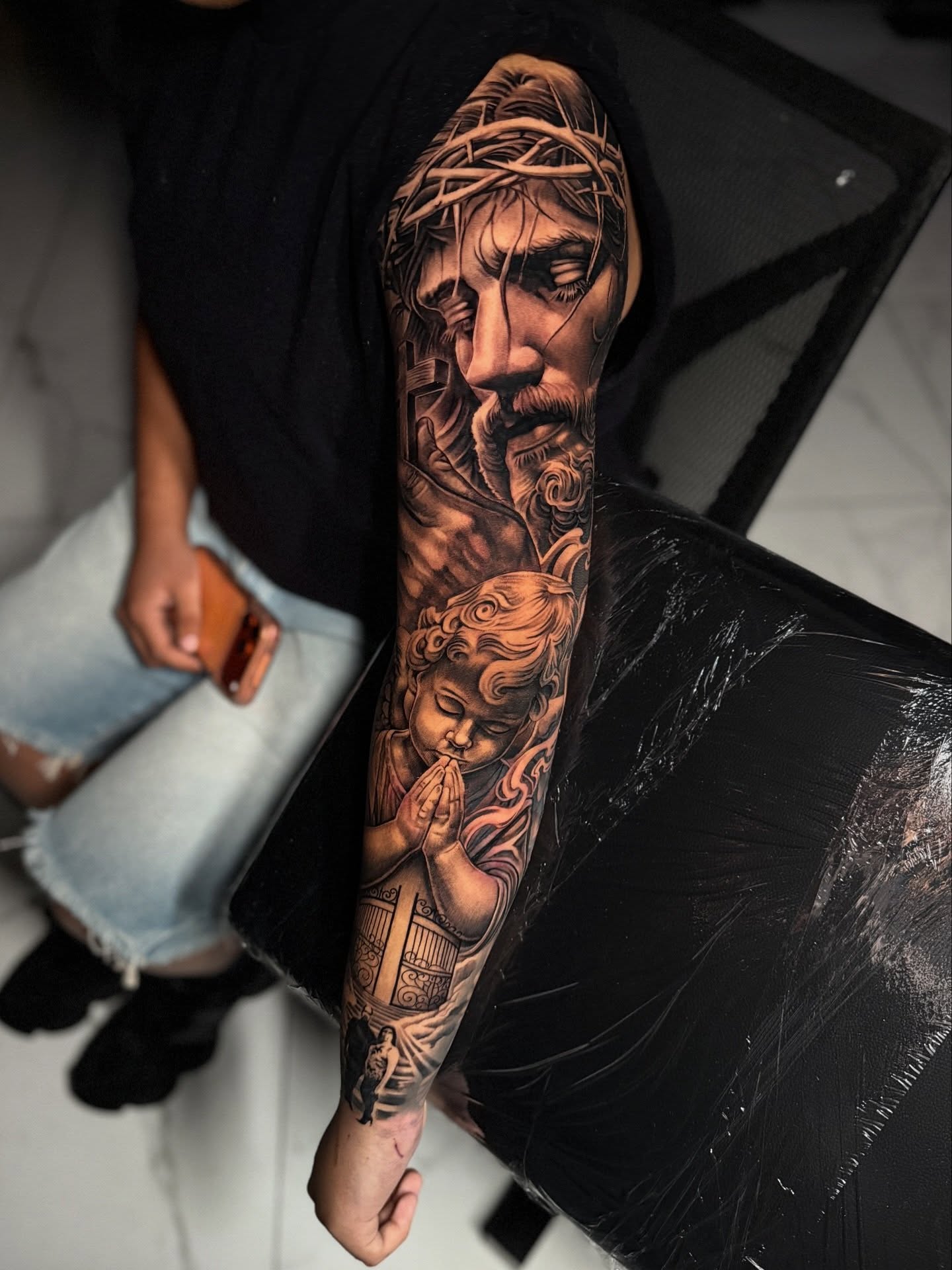 Religious scene realism tattoo on the forearm by Flames, Cerritos, California