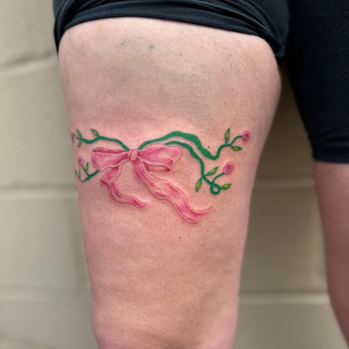 Bow and floral vine watercolor tattoo on the thigh by ✧✦ ☻ ✦✧