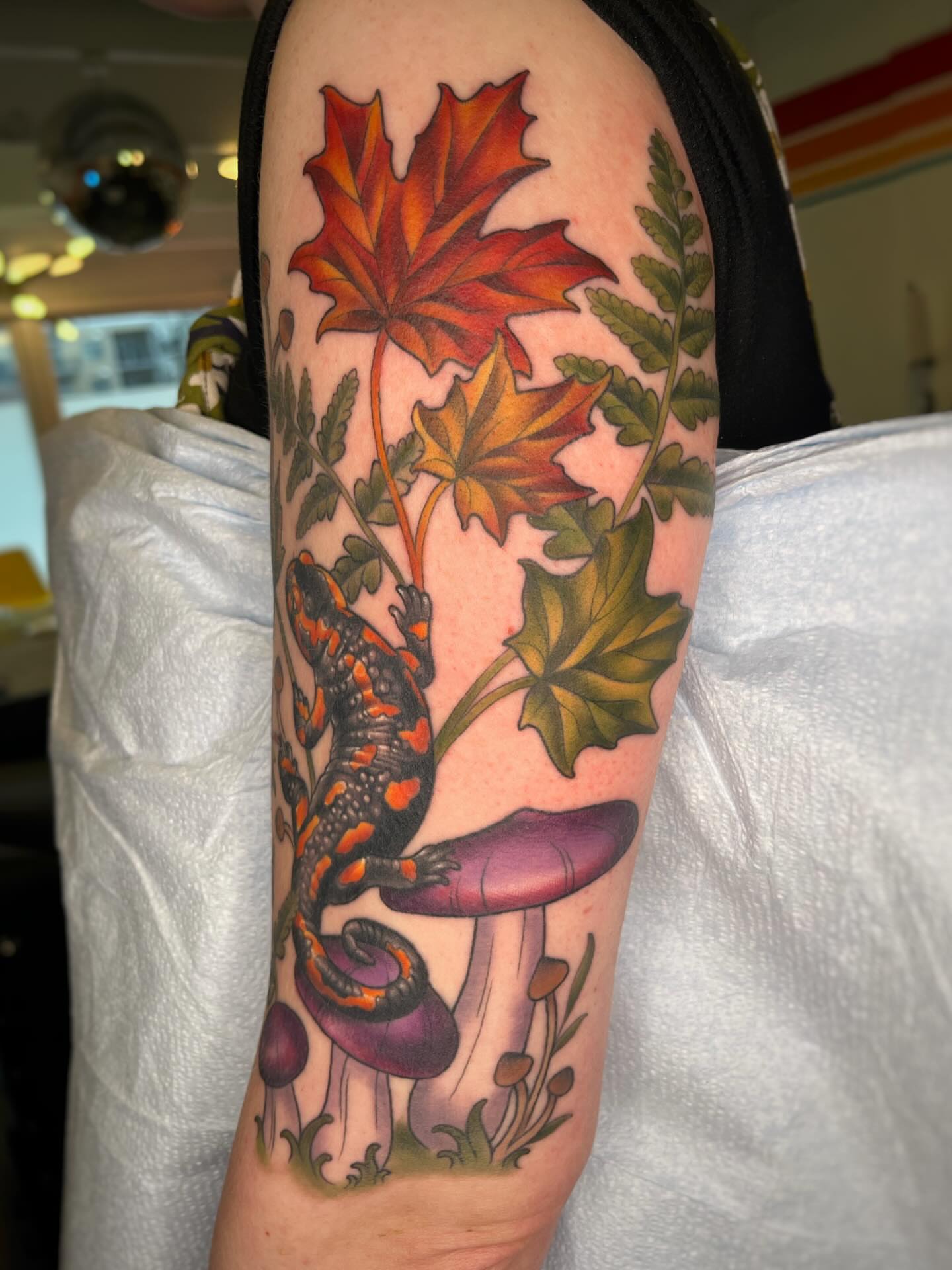 Lizard and mushrooms realism tattoo on the forearm by Emi Collison
