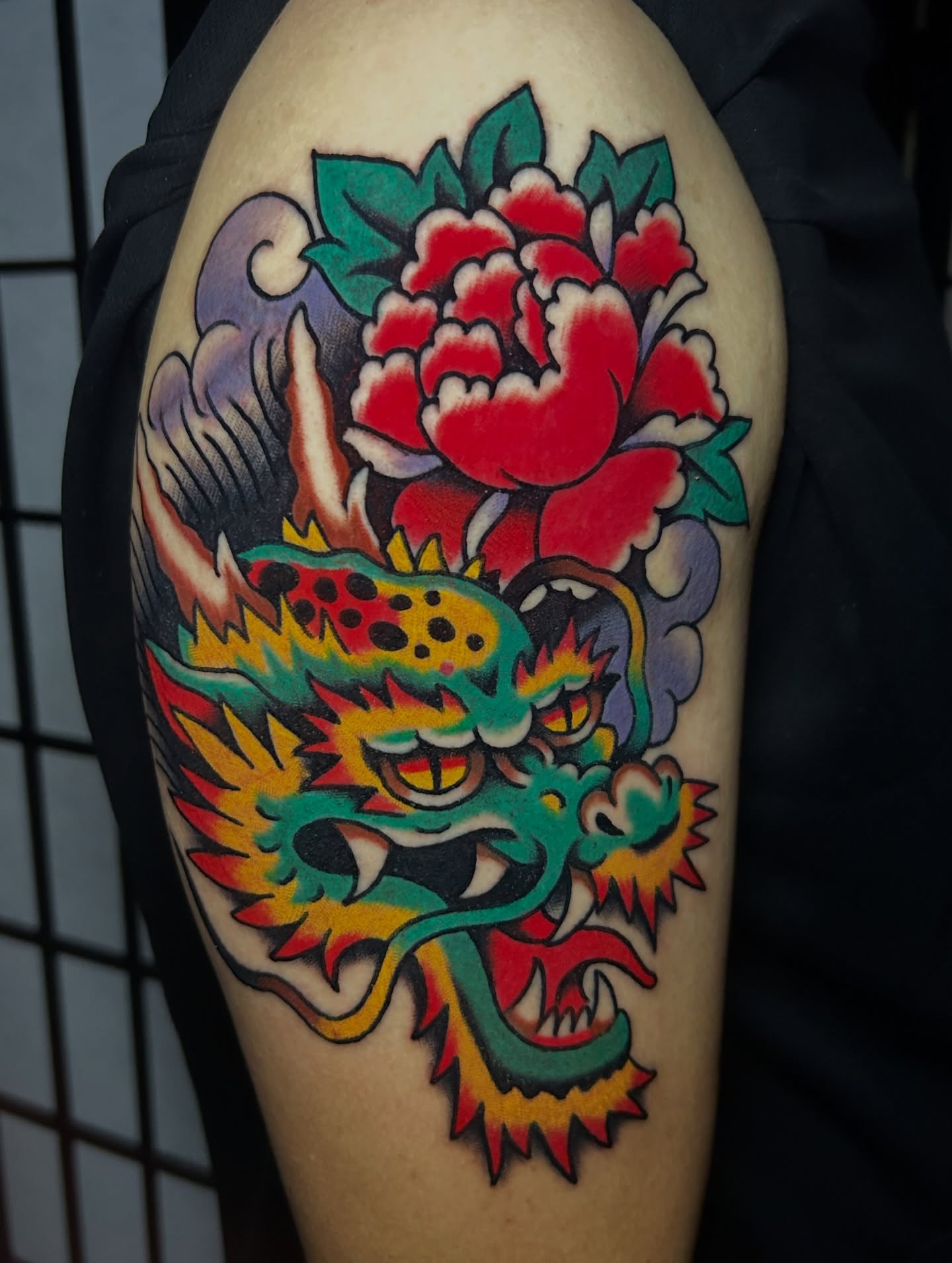 Dragon and peony American traditional tattoo on the forearm by Mitch Hoggard