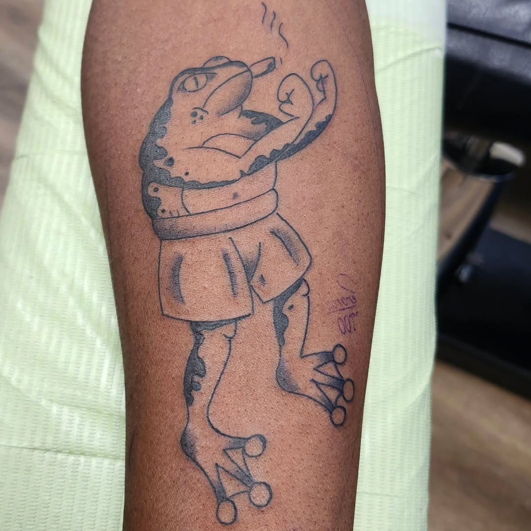 Smoking frog in shorts American traditional tattoo on the forearm by Tommy Houlihan