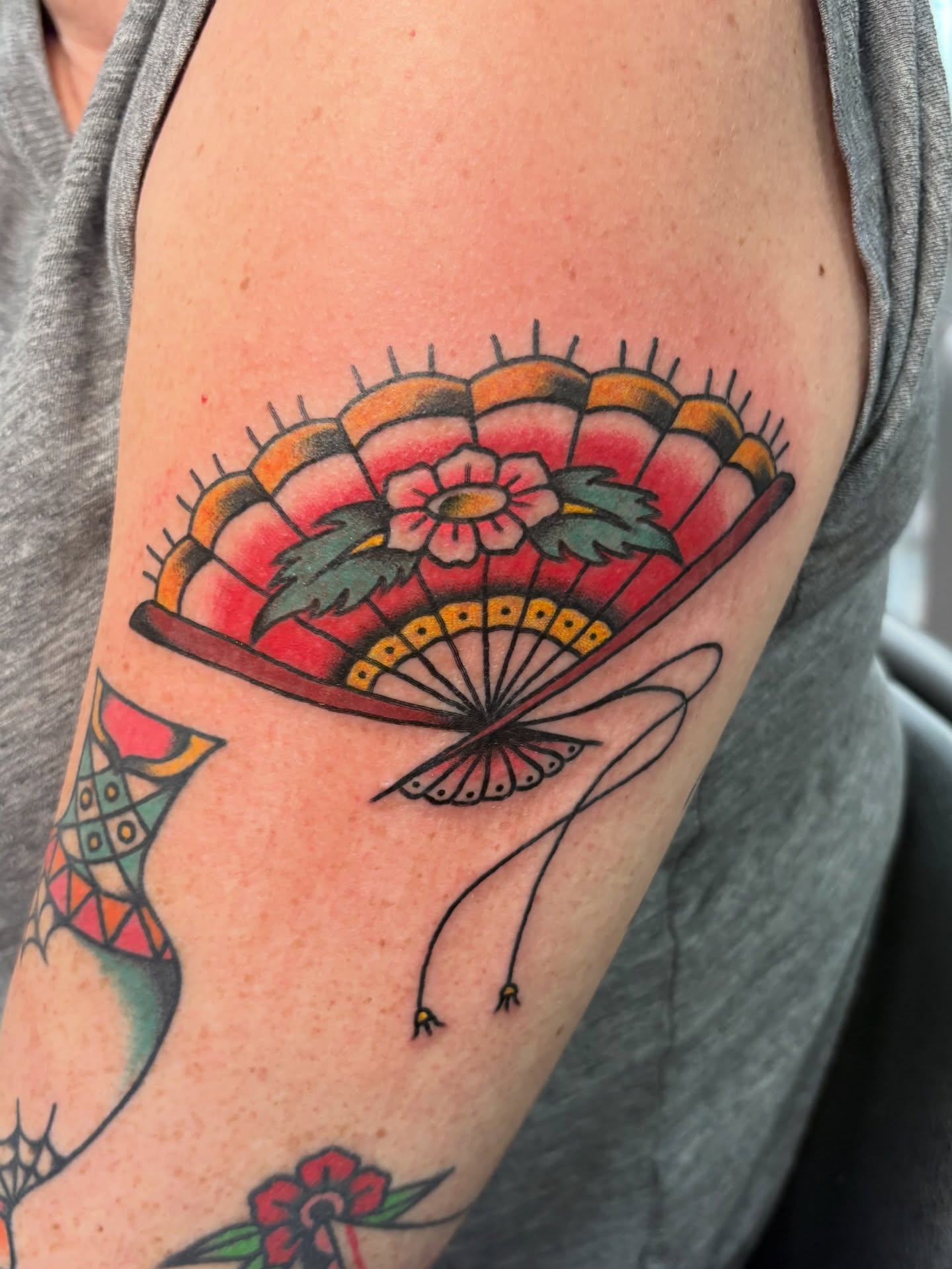 Fan with floral design American traditional tattoo on the forearm by Aysia Mankin-Wong, San Francisco, California