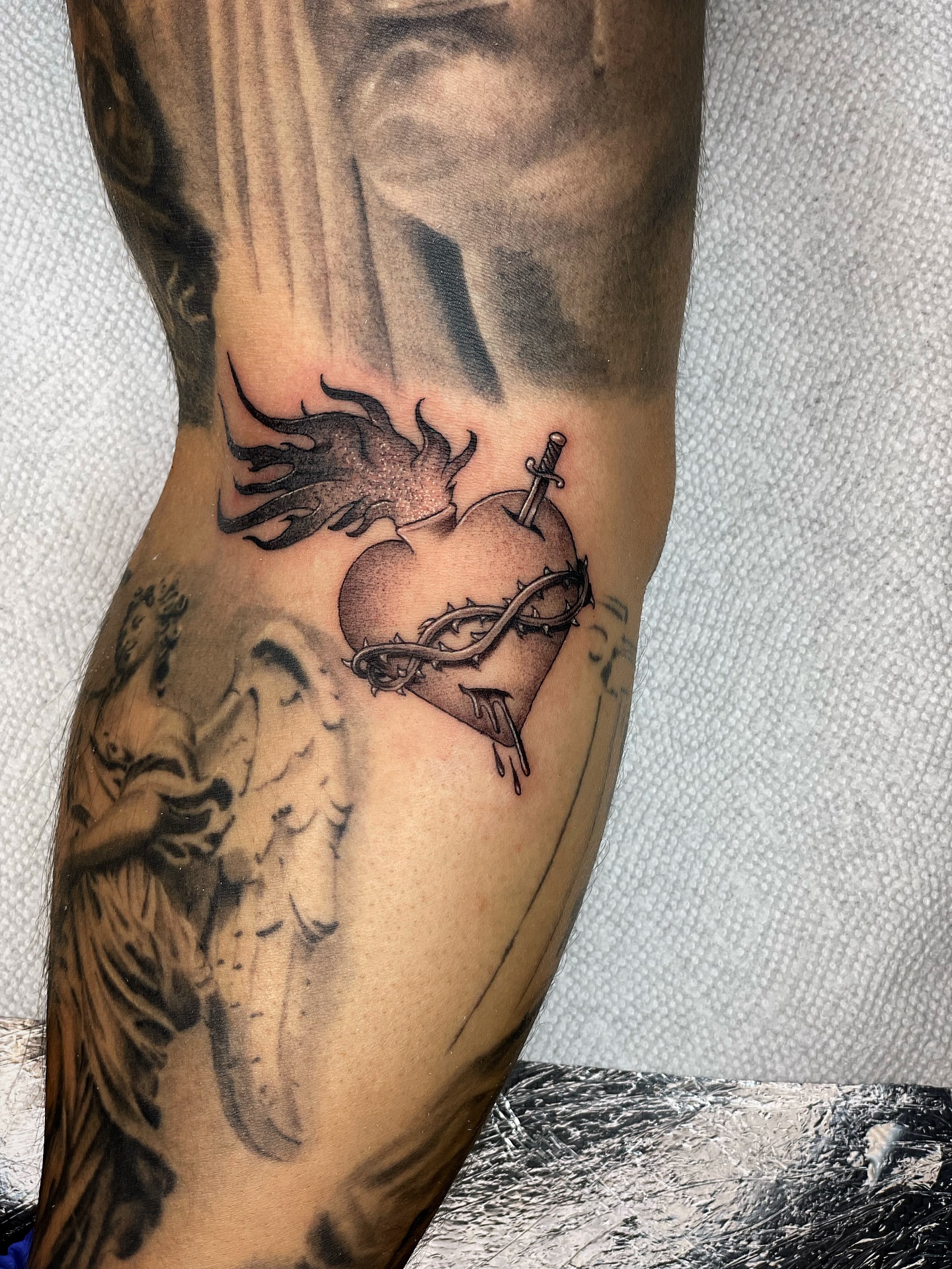 Heart with sword black and grey tattoo on the forearm by Alex Ortiz