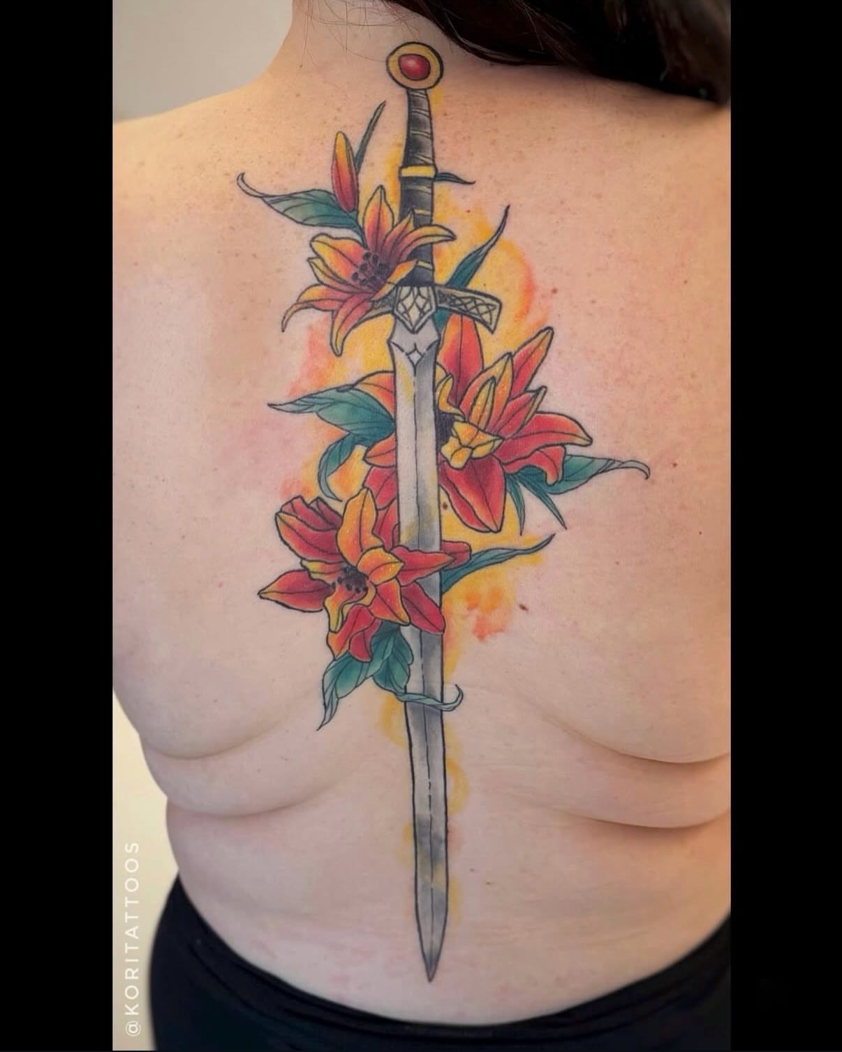 Sword and flowers watercolor tattoo on the back by Kori Millhimes