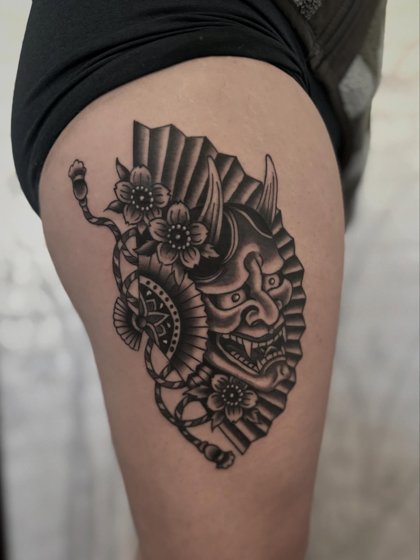 Mask with flowers and snake geometric tattoo on the thigh by Micah Norman, San Francisco, California