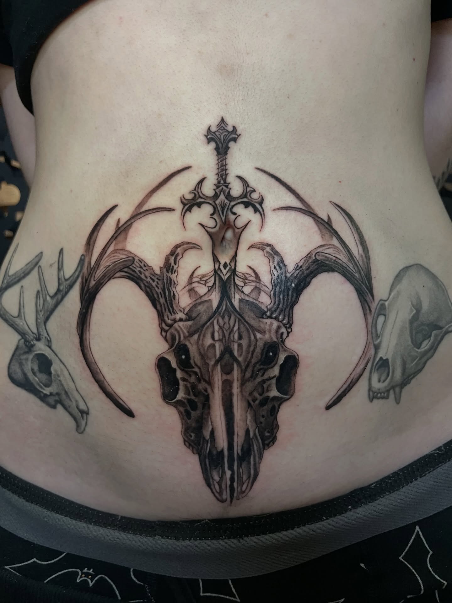 Skull and antlers geometric tattoo on the torso by Zachary Hayden