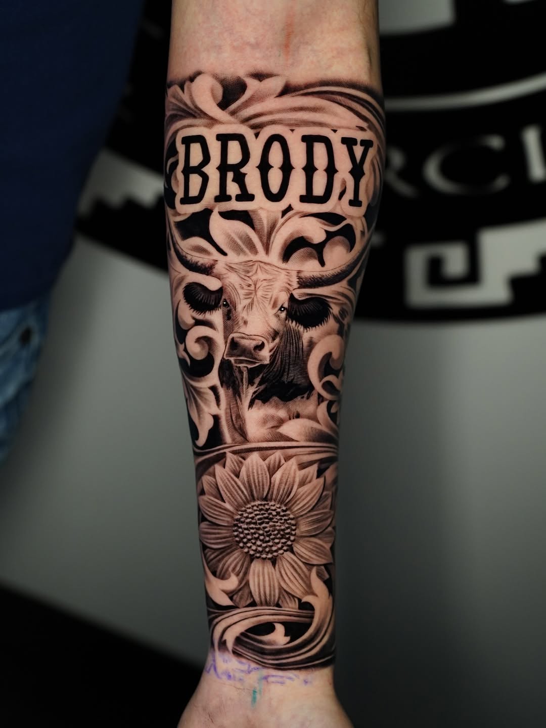 Bull head and sunflower with name realism tattoo on the forearm by Salvador Saenz Jr, Dallas, Texas
