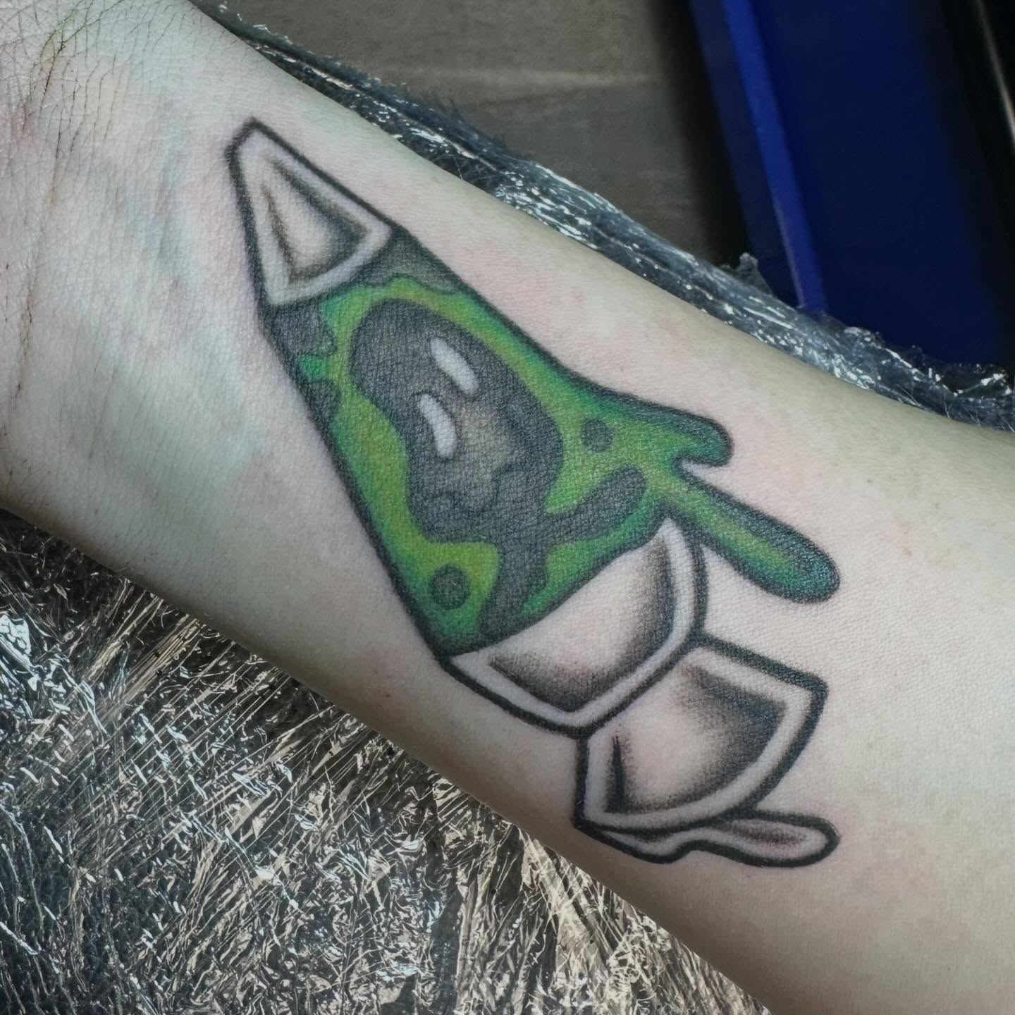 Green alien American traditional tattoo on the forearm by Mikaila Jean