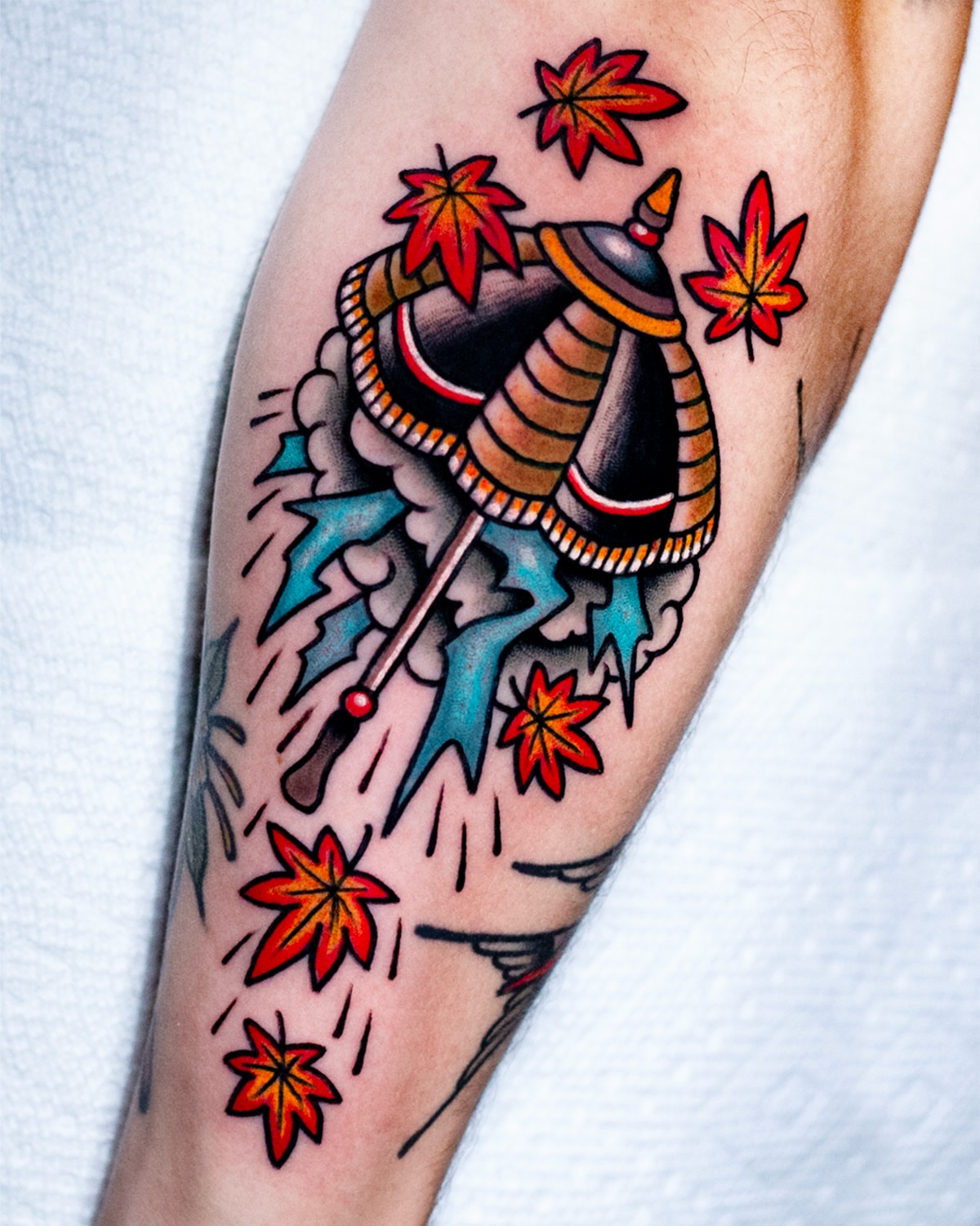 Maple leaves and samurai helmet American traditional tattoo on the forearm by Miguel Comin