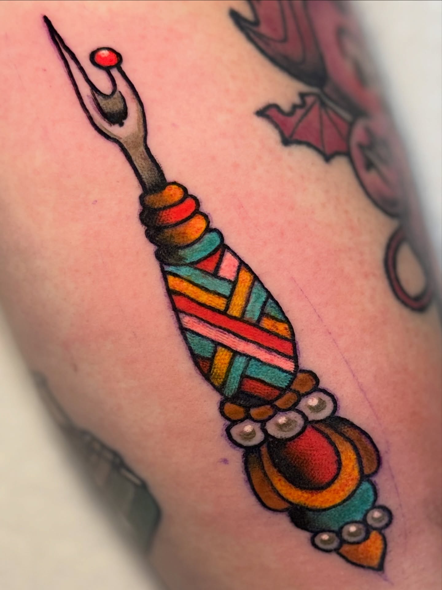 Needle and thread American traditional tattoo on the forearm by Stacey Martin Smith