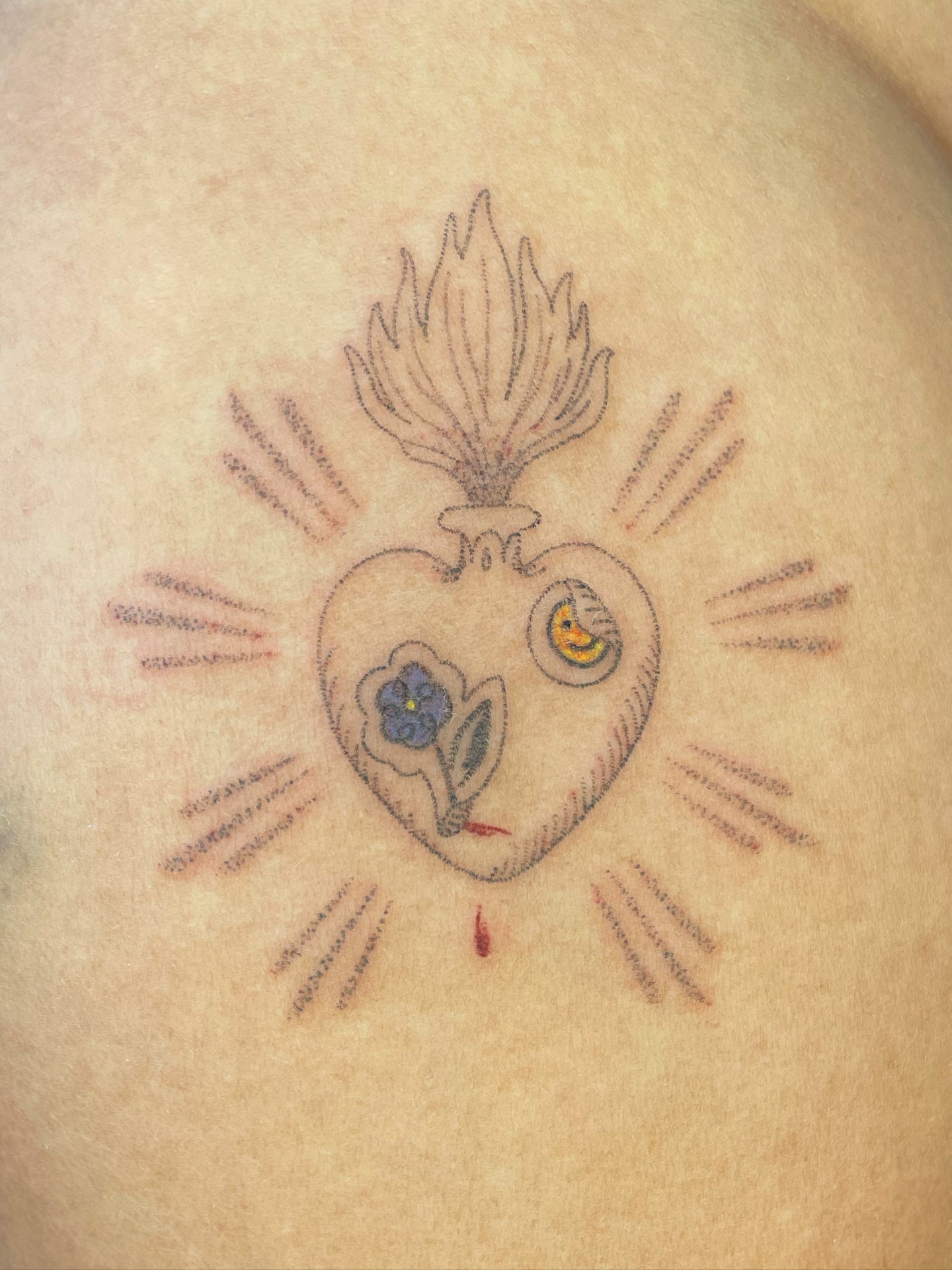 Heart with flower American traditional tattoo on the chest by cait