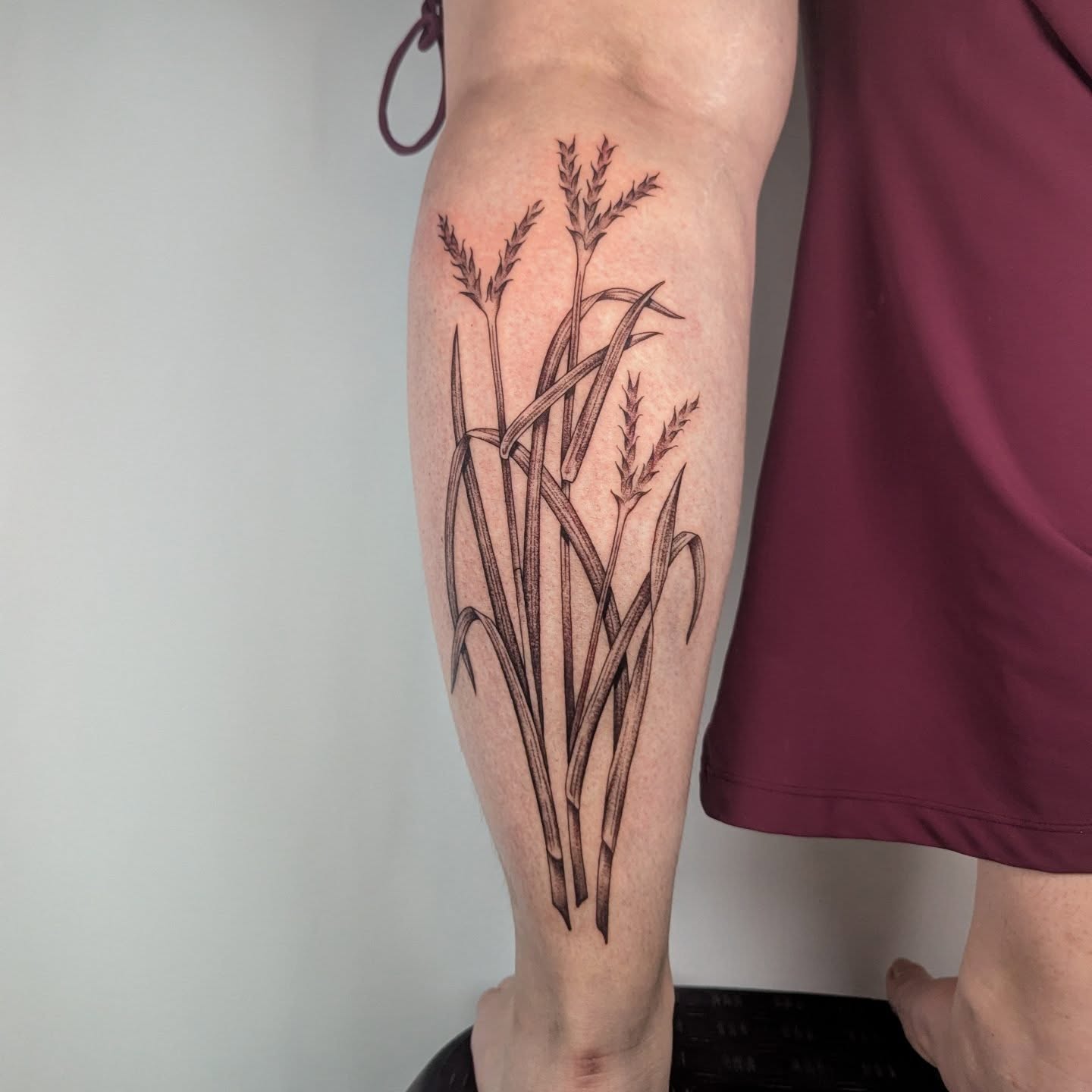 Grass black and grey tattoo on the calf by Courtney Yaddof
