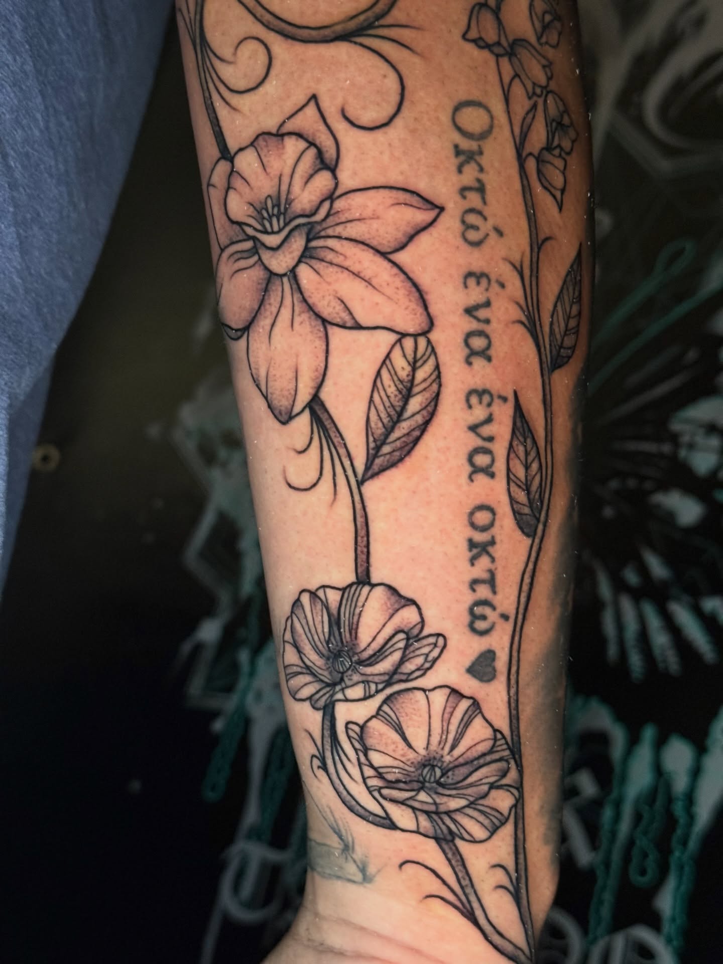 Flowers and script black and grey tattoo on the forearm by @ryanpereztattoo