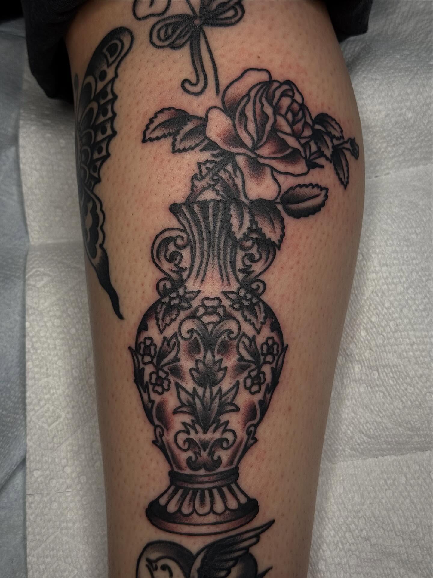 Vase with roses black and grey tattoo on the leg by Clayton - TRADITIONAL TATTOOS
