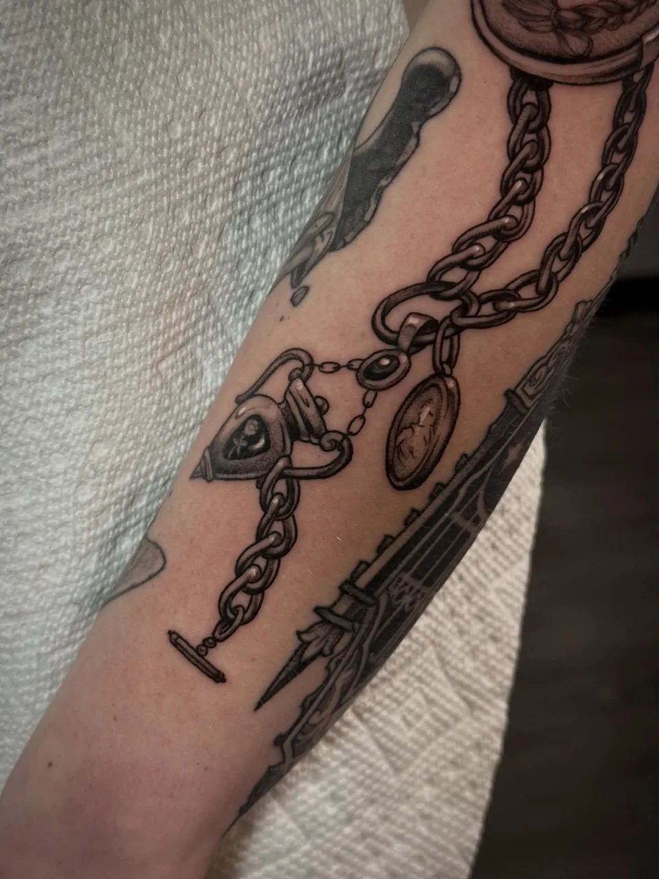 Chain and lock black and grey tattoo on the forearm by Lauren Vandevier