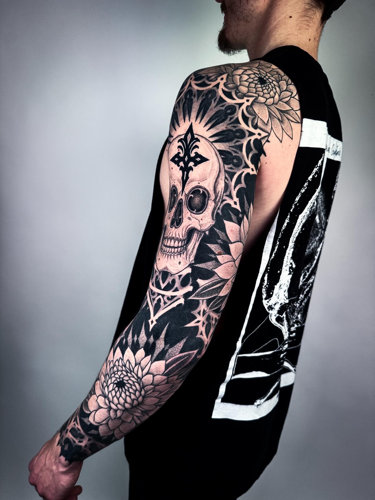 Skull with fleur-de-lis realism tattoo on the upper arm by Aries Rhysing, Wheat Ridge, Colorado