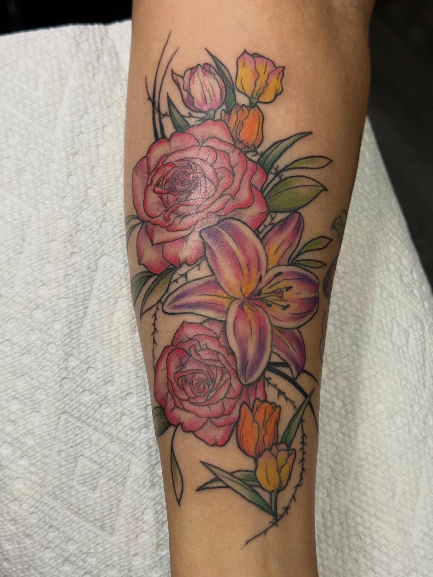 Floral bouquet realism tattoo on the forearm by Camryn Justice