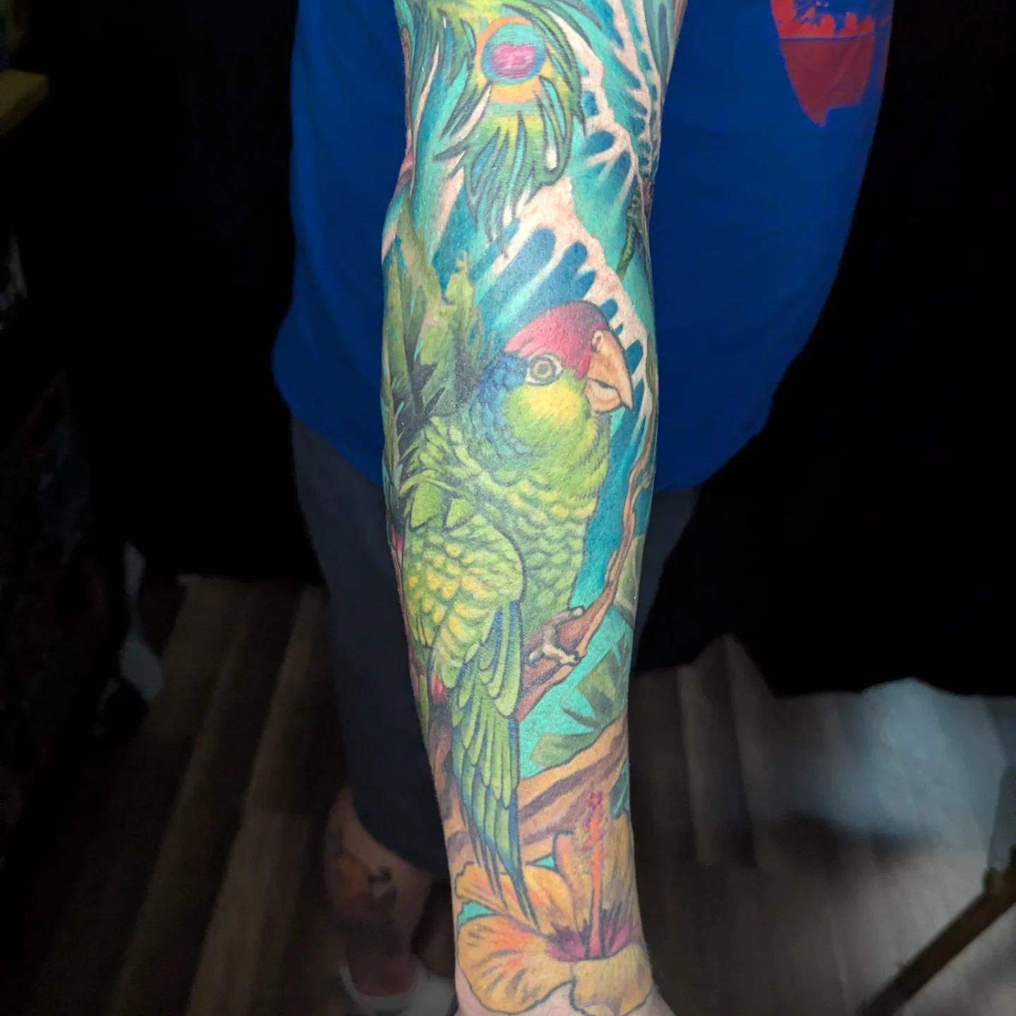 Parrot and tropical foliage new school tattoo on the forearm by Devon Greig
