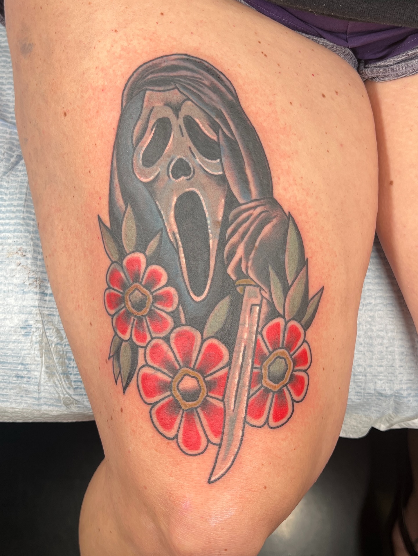 Ghost mask with flowers American traditional tattoo on the thigh by Brian Mock