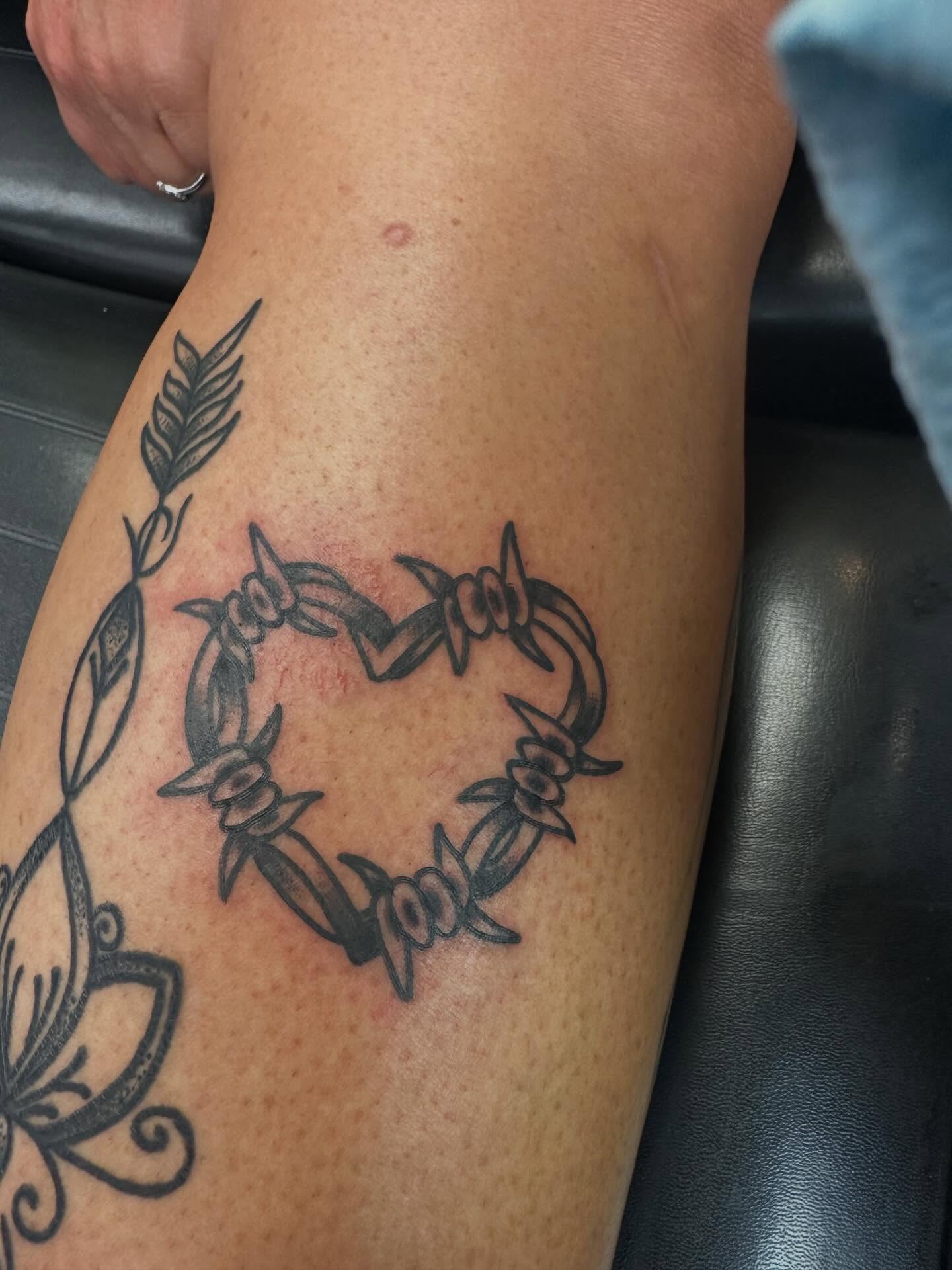 Barbed wire heart black and grey tattoo on the thigh by Zach Eden