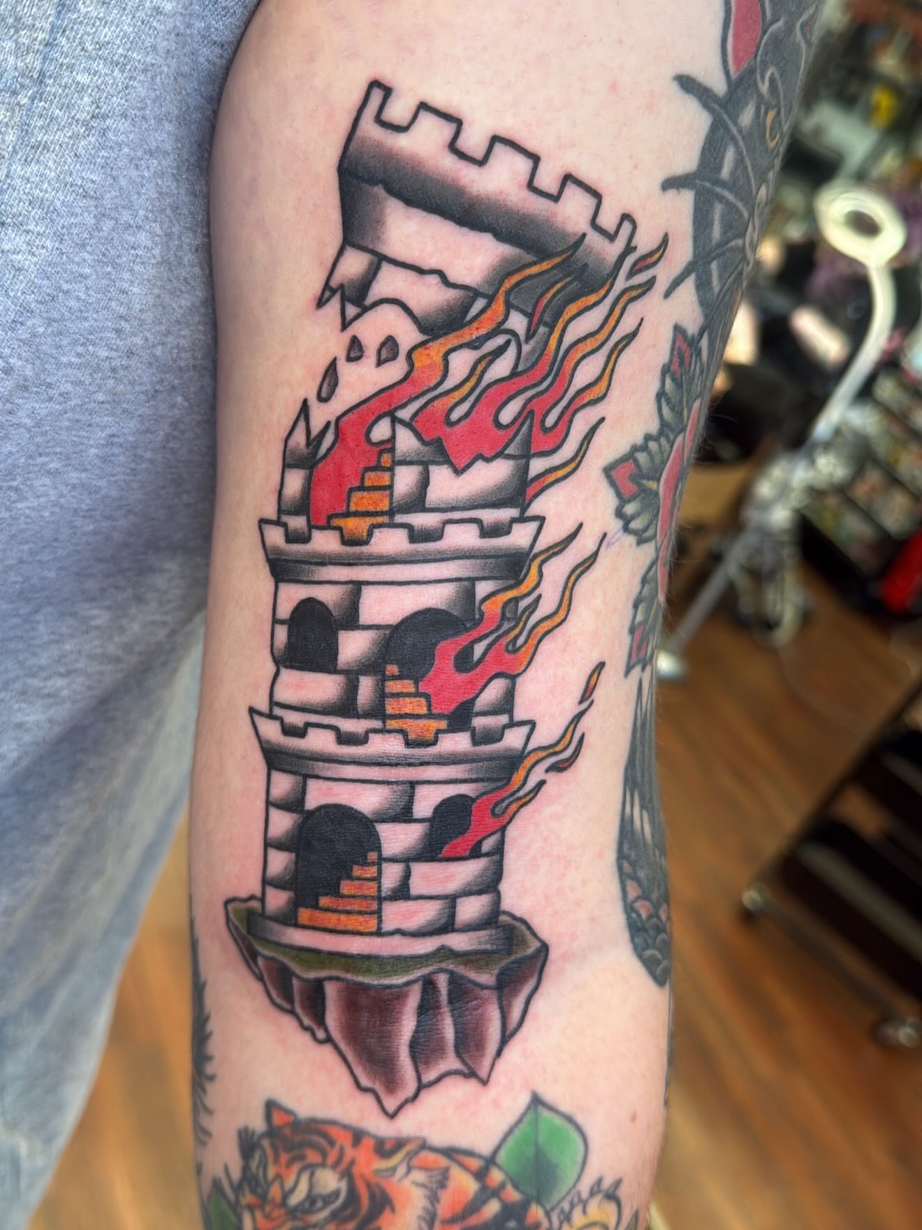 Castle with flames American traditional tattoo on the forearm by Zach Eden