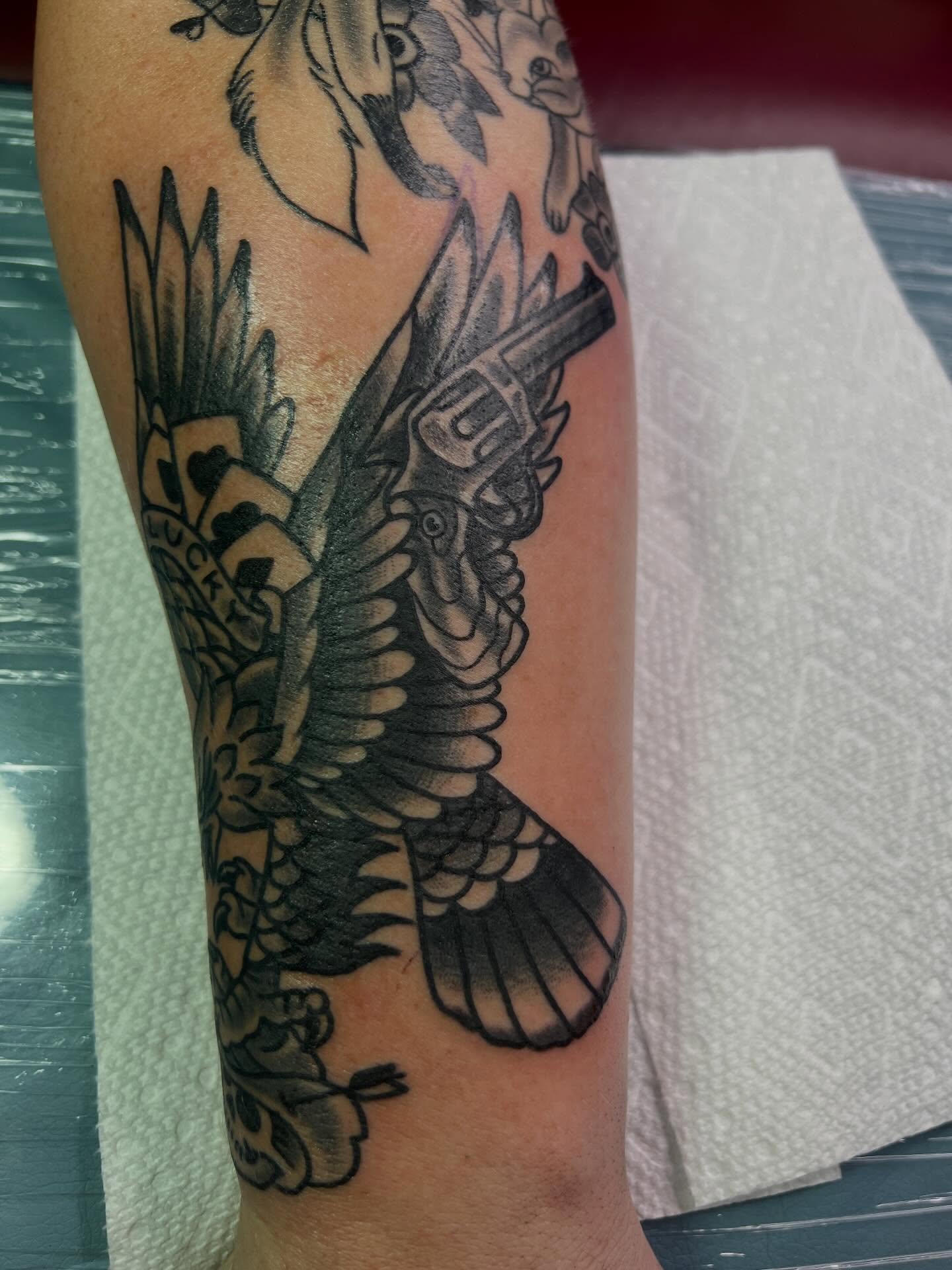 Bird with gun American traditional tattoo on the forearm by Steven Blackheart