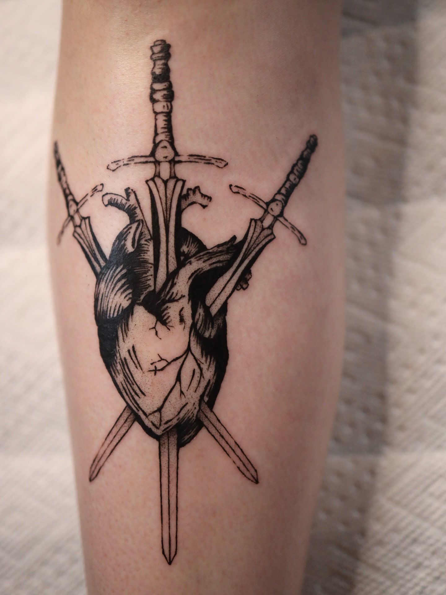 Heart with swords black and grey tattoo on the forearm by morgan purcey