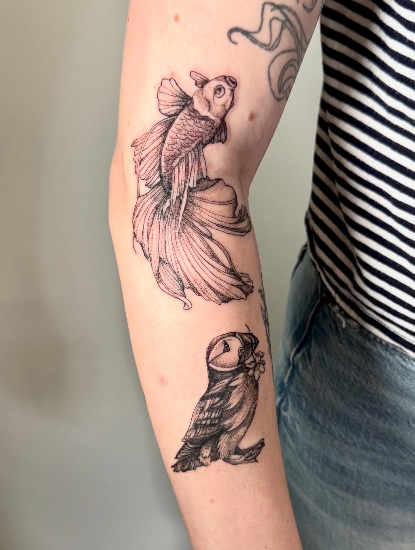 Goldfish and puffin black and grey tattoo on the forearm by C.J. Pennington