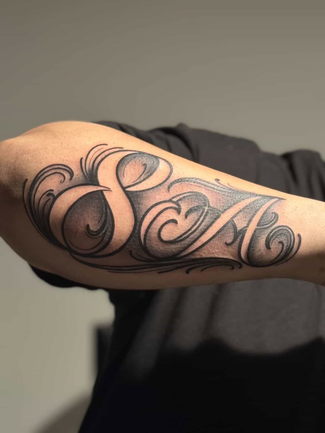 Script lettering with swirls lettering tattoo on the forearm by Dallas tx tattoo artist ✝️