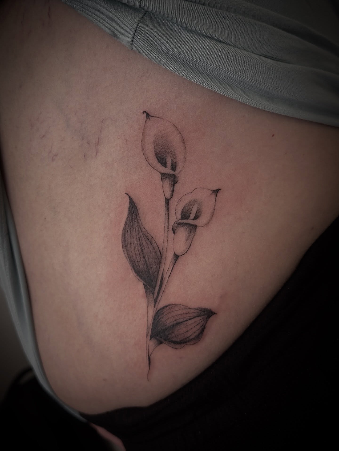 Calla lilies black and grey tattoo on the thigh by Matt Kearney